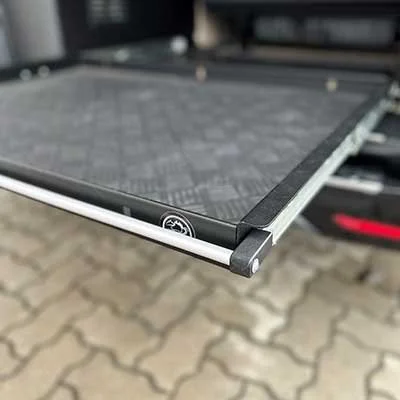 Leiter für eine Tiertransportbox auf einem Fahrzeug, mit schwarzem Rahmen und Ketten in der Ecke, auf einem gepflasterten Boden