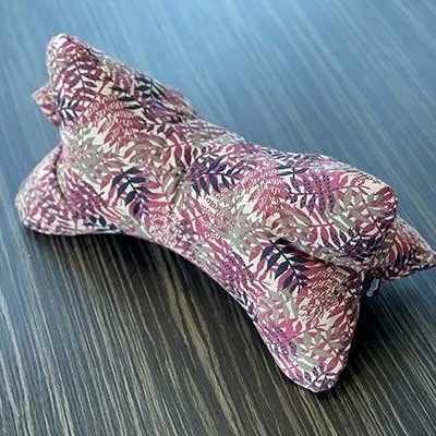 Ein Stofftier in Form eines Hundes mit buntem Blättermuster auf einem Tisch.
