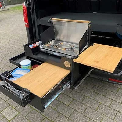 Ausziehbare Küchenarbeitsfläche und Grill im Kofferraum eines Autos.