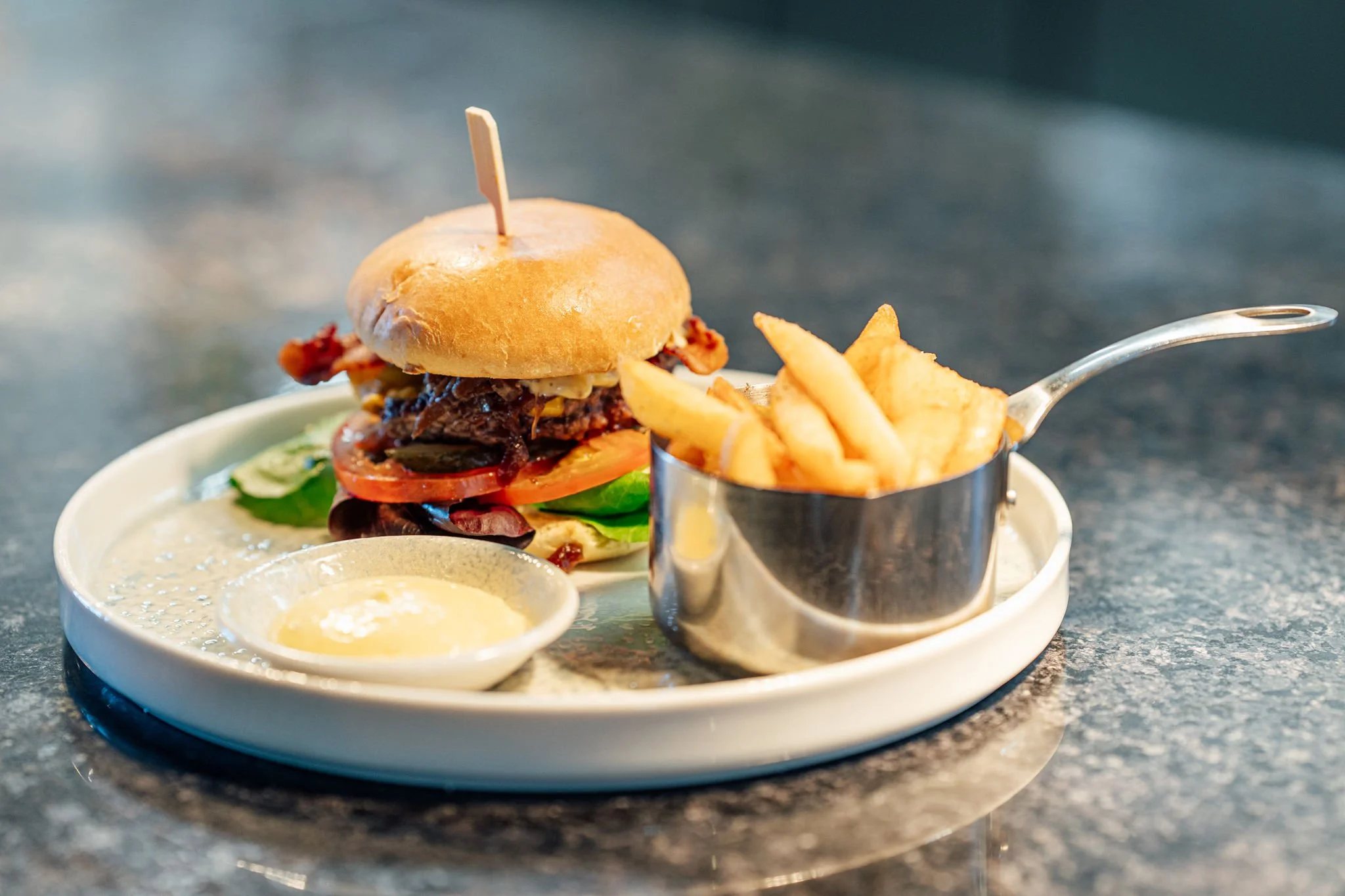 Bilde av en hamburger med pommes frites på en tallerken.