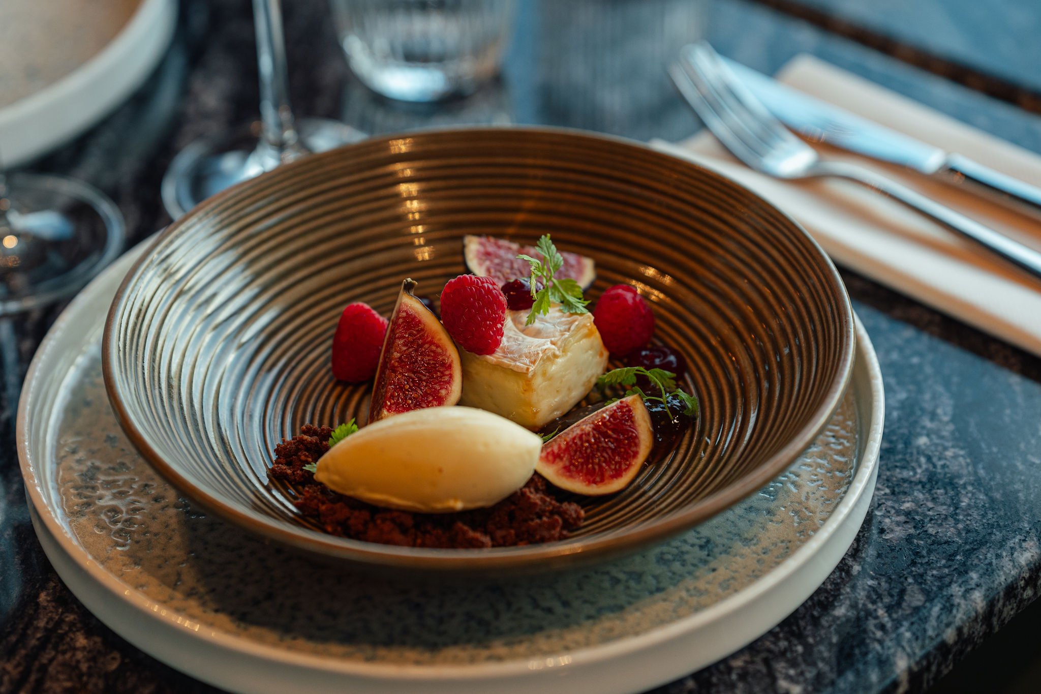 En dessert med fersken, bringebær og krem i en skål på en tallerken.