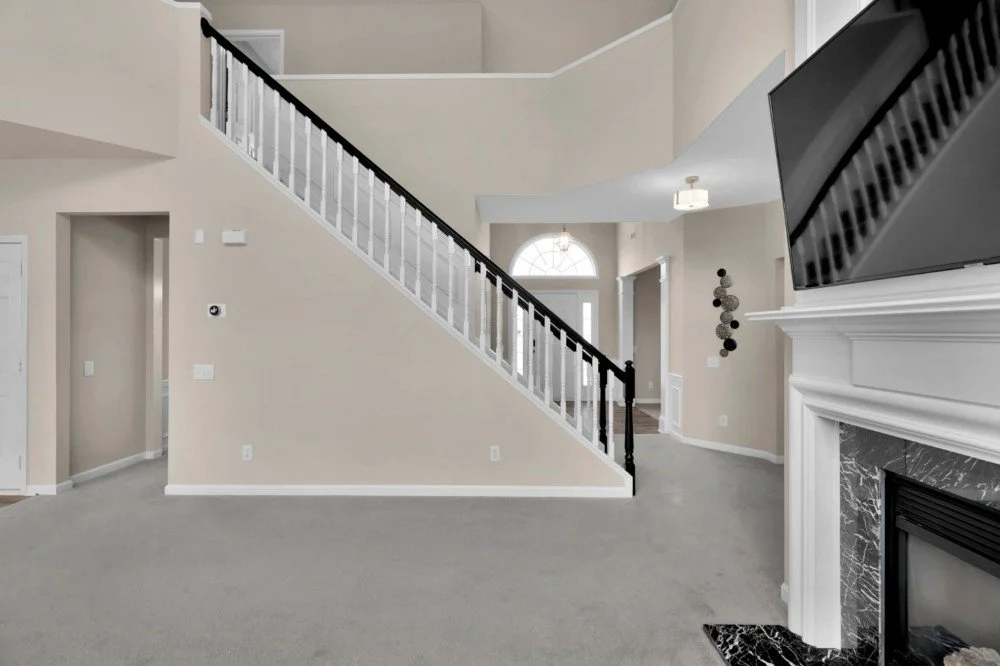 Empty living room with a staircase and fireplace in a modern home.