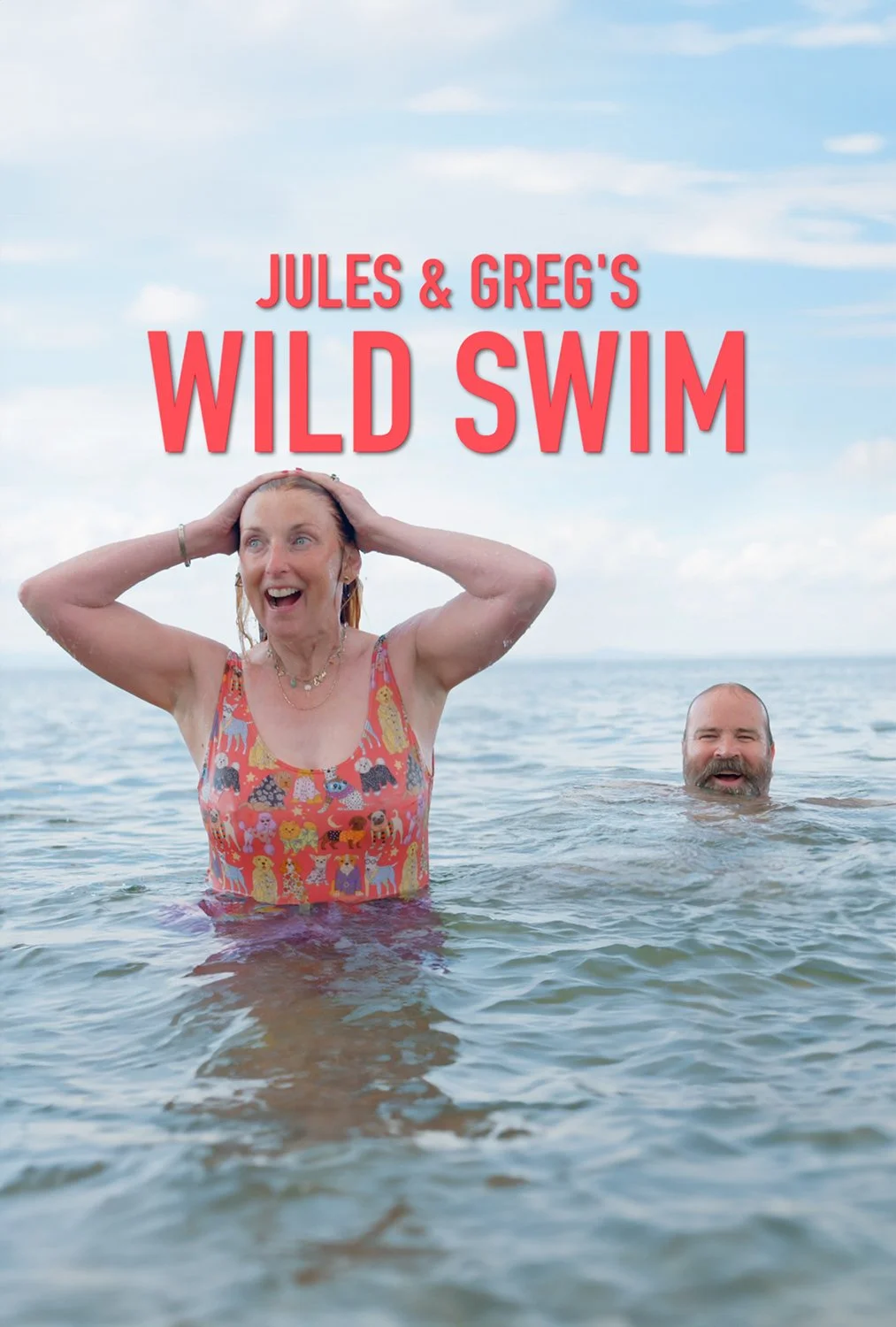 Two people, a woman and a man, are swimming in the ocean. The woman is smiling with her hands on her head, wearing a colorful swimsuit with animal prints. The man is partially submerged, smiling, with only his head visible. The background shows a partly cloudy sky.