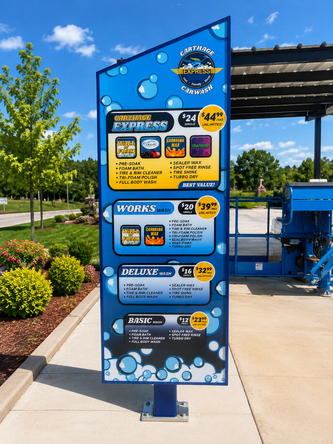 Car wash price menu sign listing various wash packages and prices, with descriptions of services included for each package, set outdoors with a blue sky, trees, and flowers nearby.