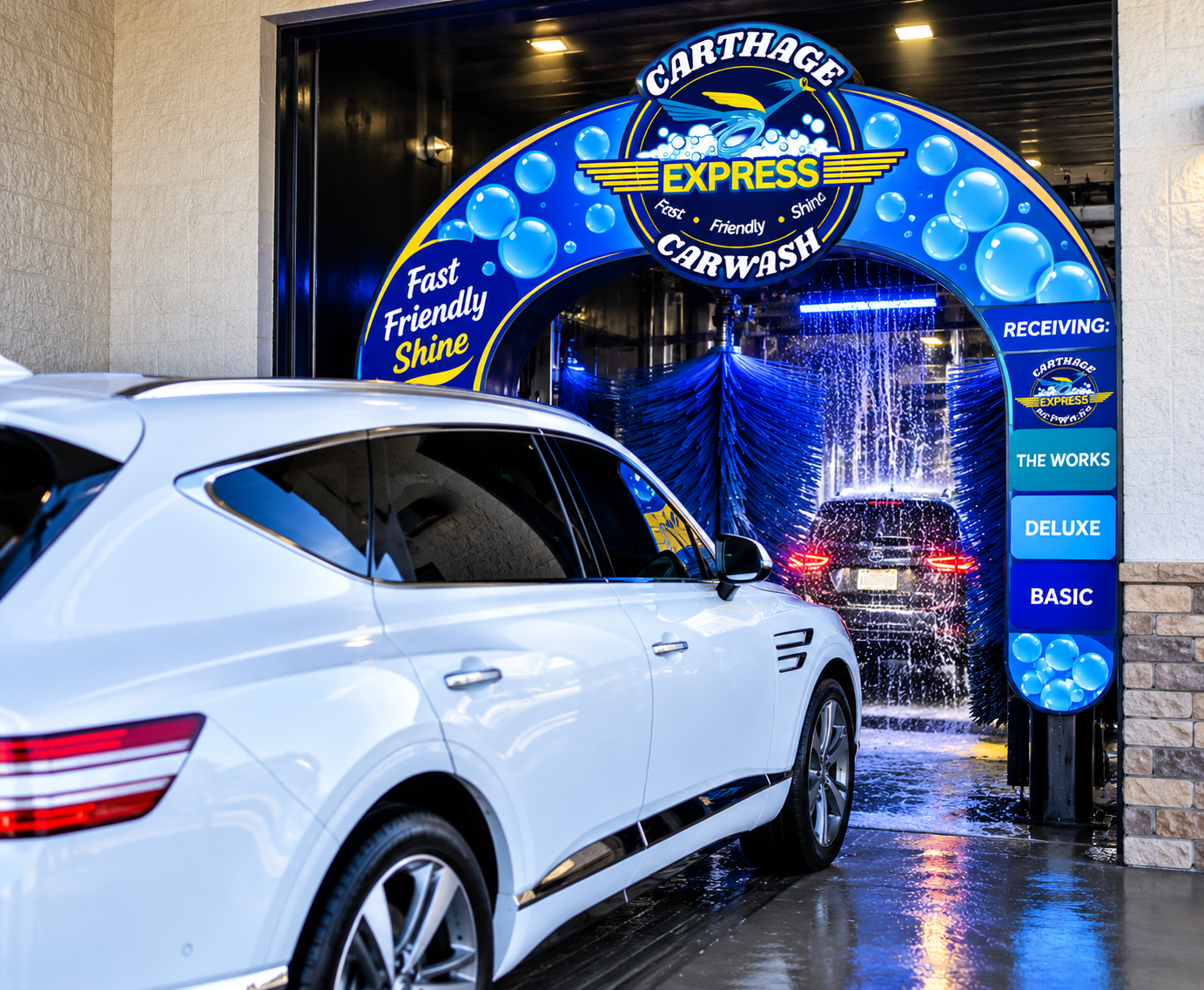 A white car at a car wash named Carthage Express Carwash, with a blue and yellow sign displaying the service options and a car being rinsed with water and soap. The car wash is equipped with a rotating brush and water spray system.