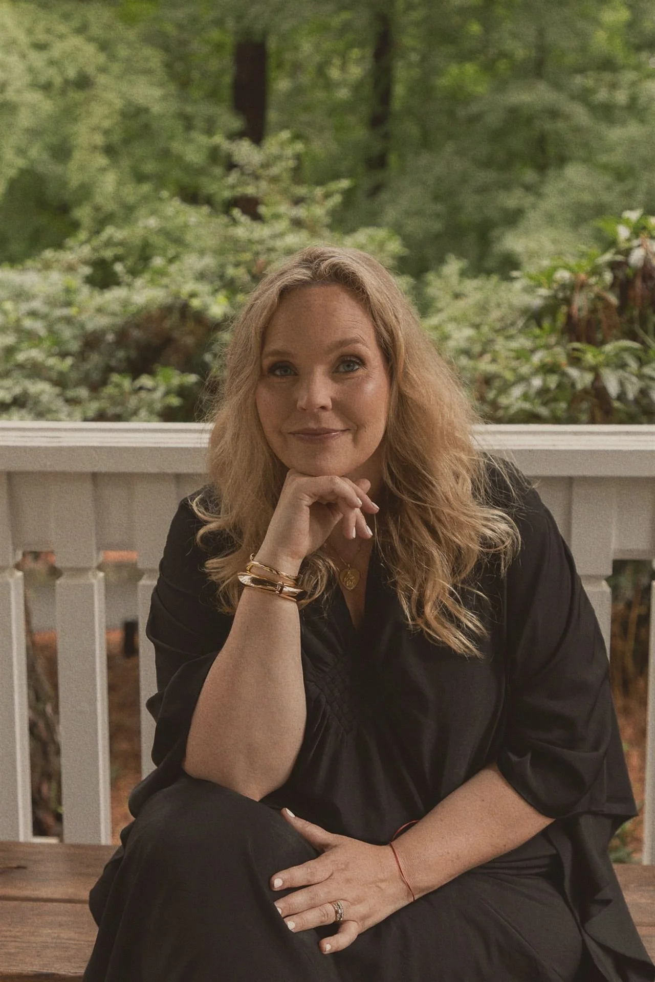 Danielle Hendrickson, Sacred Feminine spiritual coach, seated on a garden porch with her chin resting in her hand