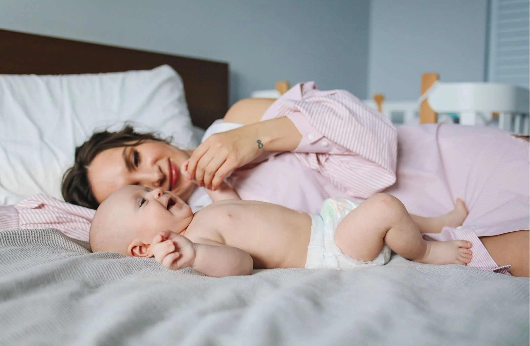 Smiling mother cuddling her laughing baby on a bed
