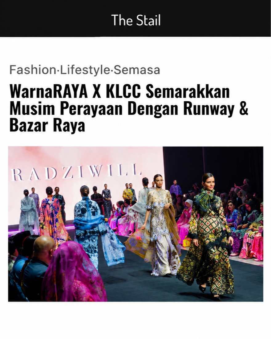 Models walking down the runway at a fashion show, wearing traditional and modern batik clothing, with audience members seated on either side and a large pink backdrop with 'RADZIWILL' written on it.
