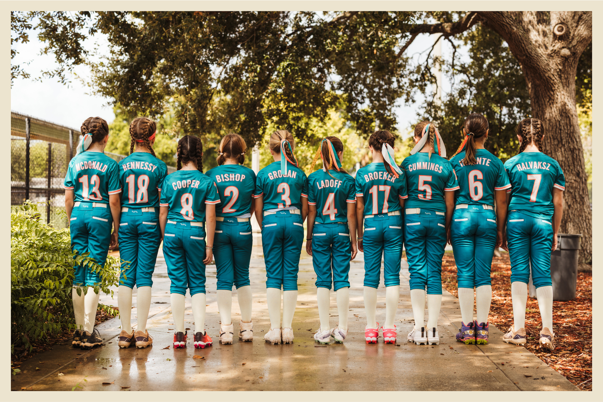 Boca Vibe 10U softball players lined up in teal uniforms beneath a large tree.