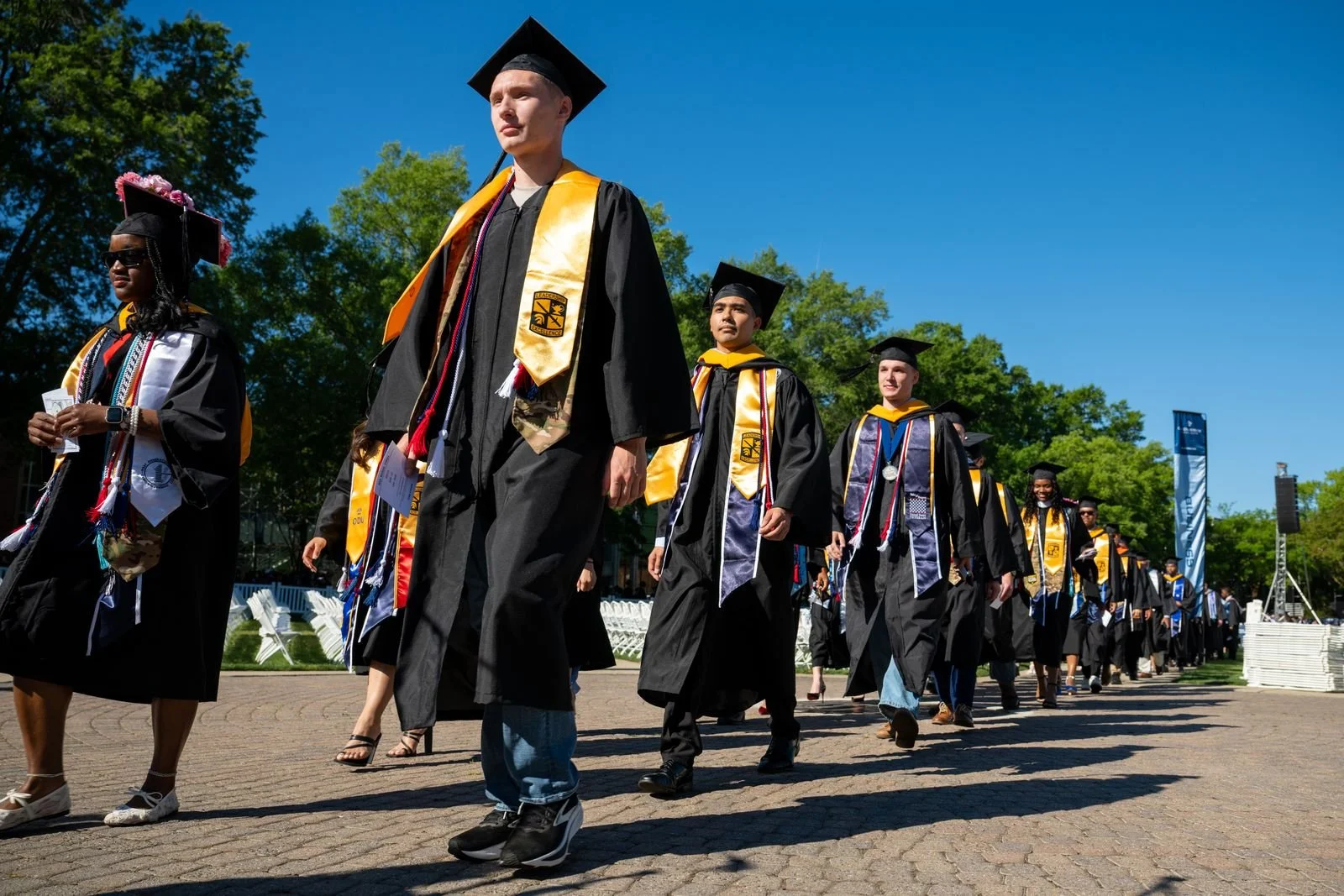 Old Dominion University graduates walking together during an outdoor commencement ceremony.