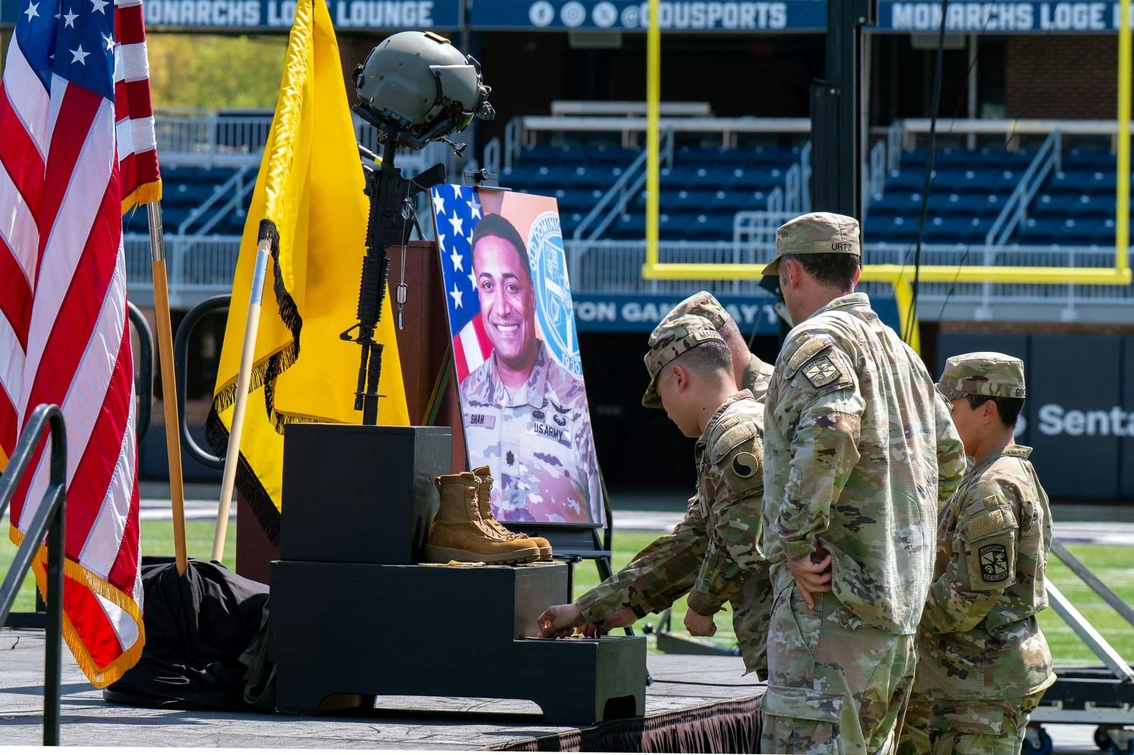 Memorial ceremony honoring LTC Brandon A. Shah with American flags, portrait, helmet and boots.