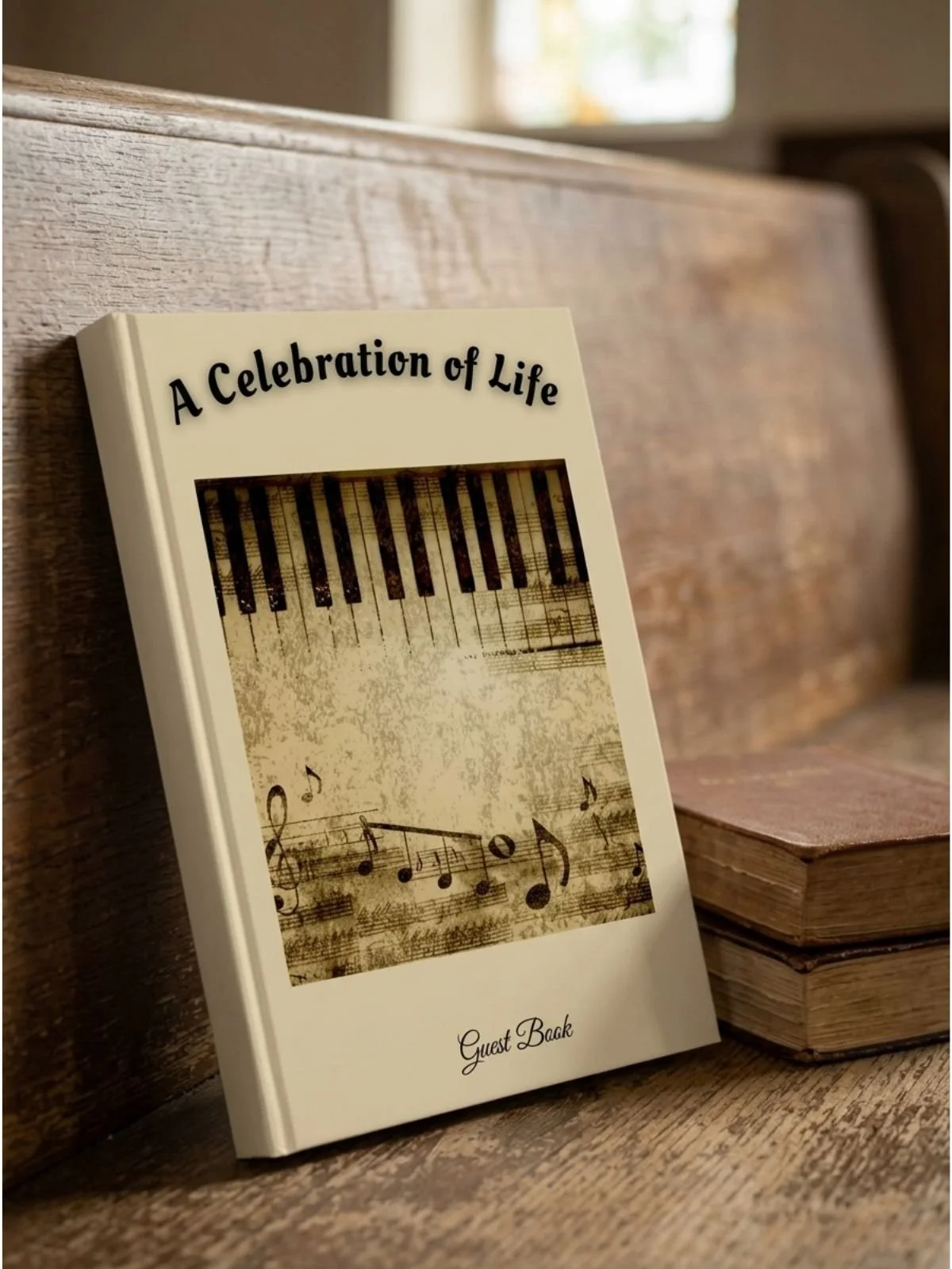 A guest book with the title 'A Celebration of Life' resting against a wooden surface, with a blurred background of a window and more wood.