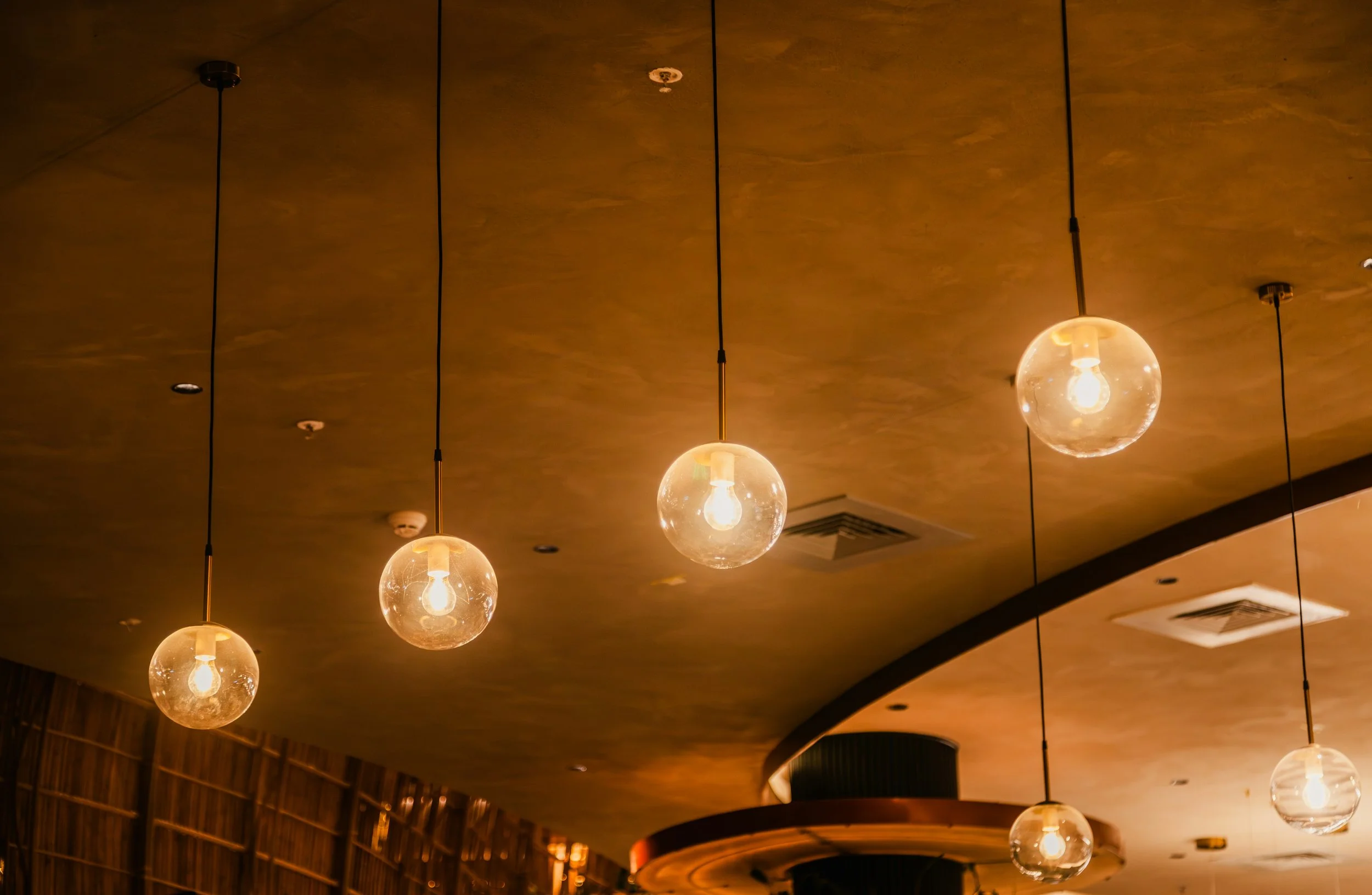 Ceiling illuminated globular pendant lights in a warm-colored interior space.