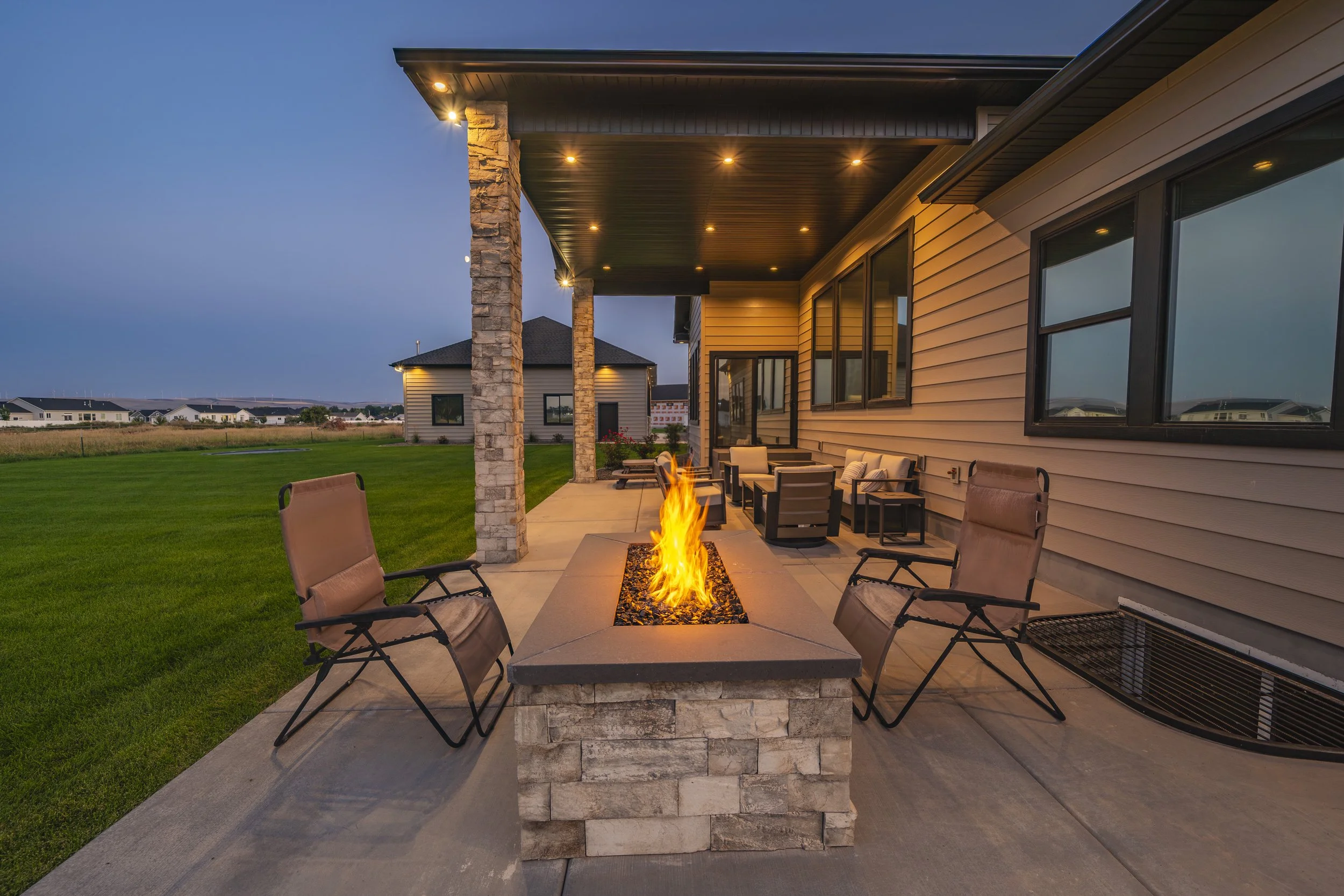 Covered patio seating around a fire pit at dusk — JAB Construction’s Timeless Craftsman custom home in Iona, Idaho.