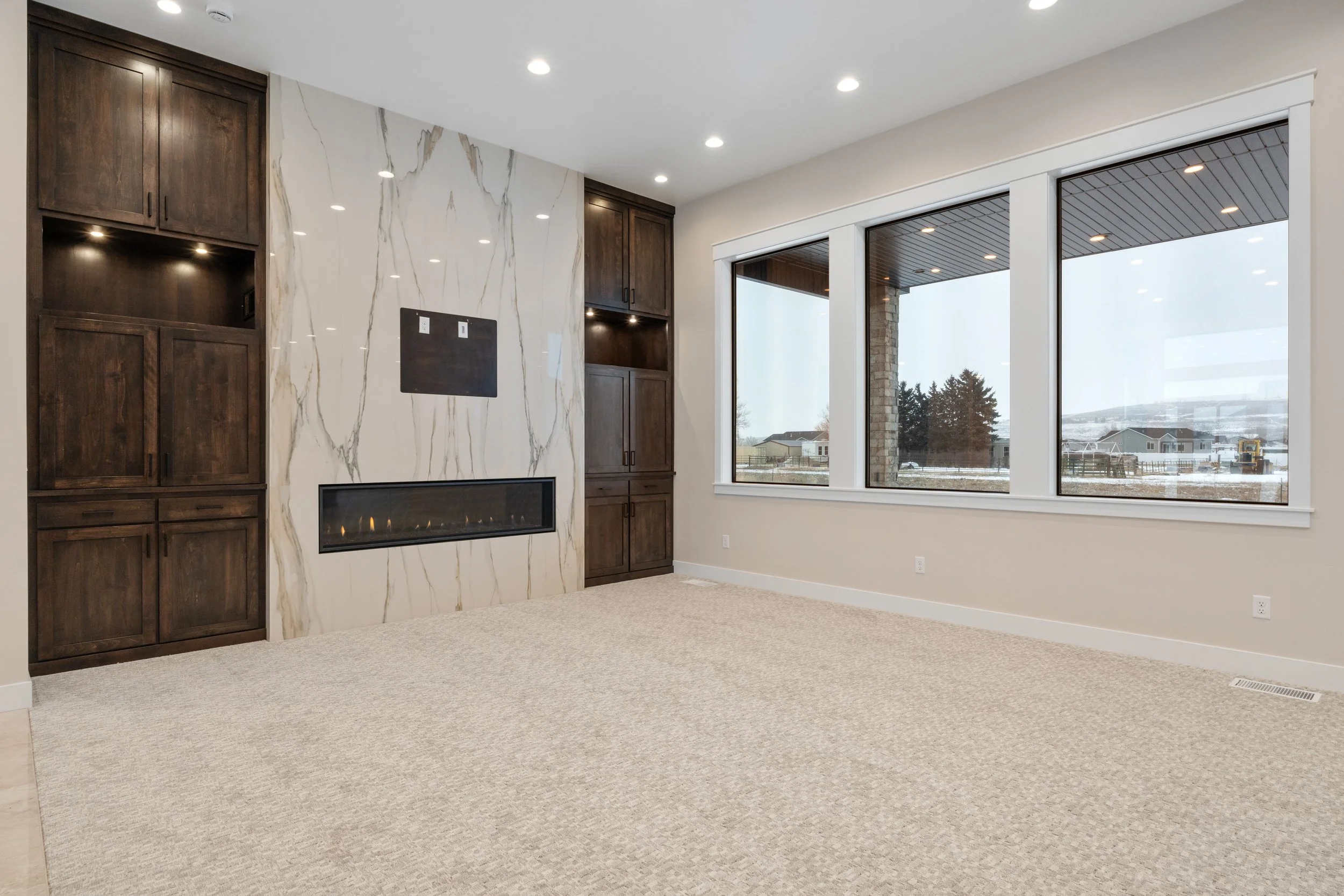 Living room fireplace beside large windows — JAB Construction’s Timeless Craftsman custom home in Iona, Idaho.