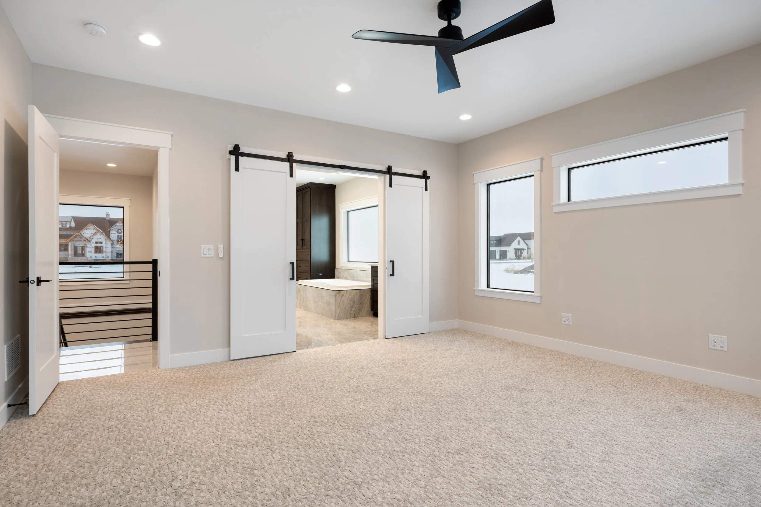 Bedroom with barn doors and a ceiling fan — JAB Construction’s Timeless Craftsman custom home in Iona, Idaho.