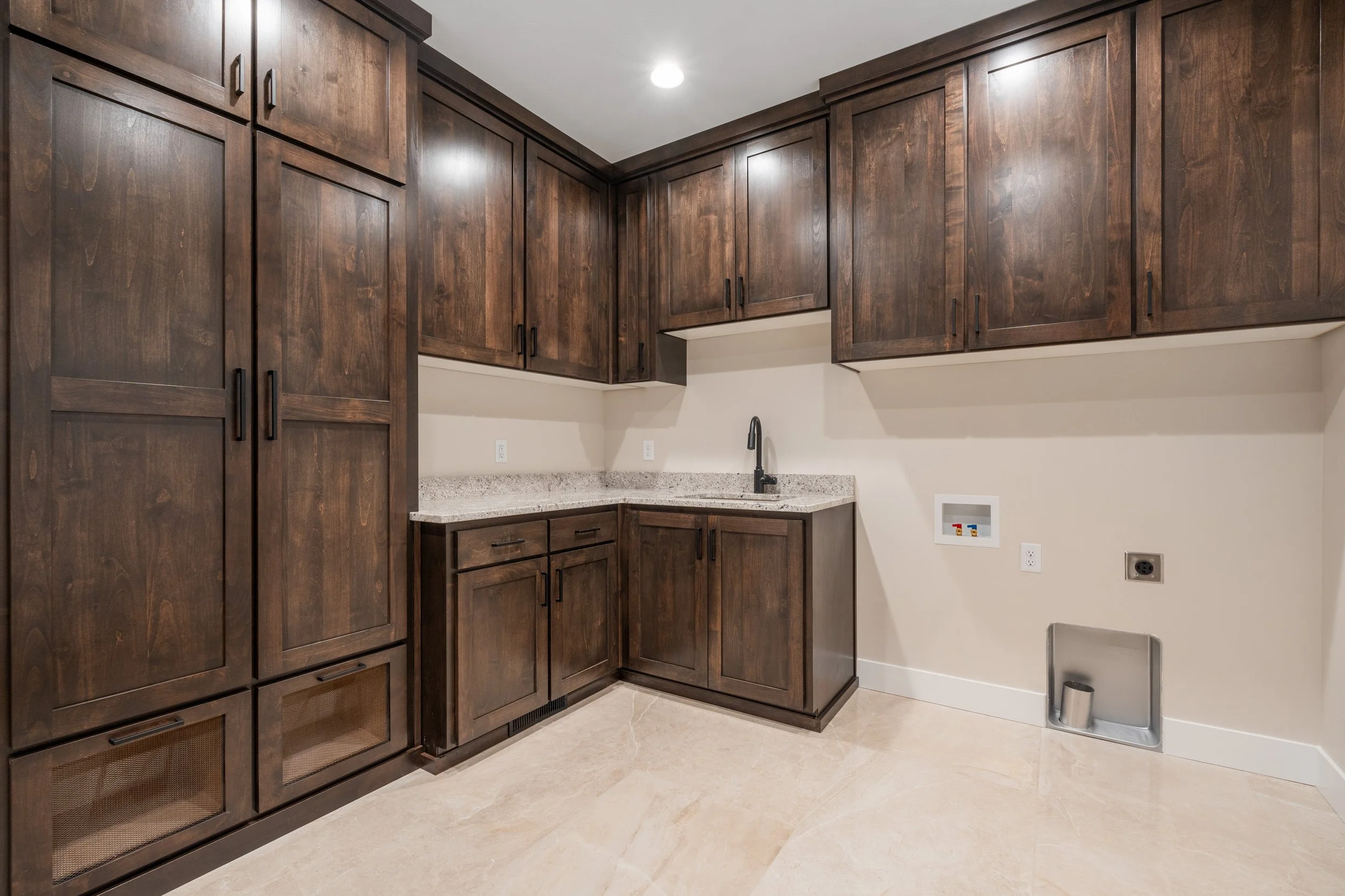 Laundry room with dark wood cabinets and a sink — JAB Construction’s Timeless Craftsman custom home in Iona, Idaho.
