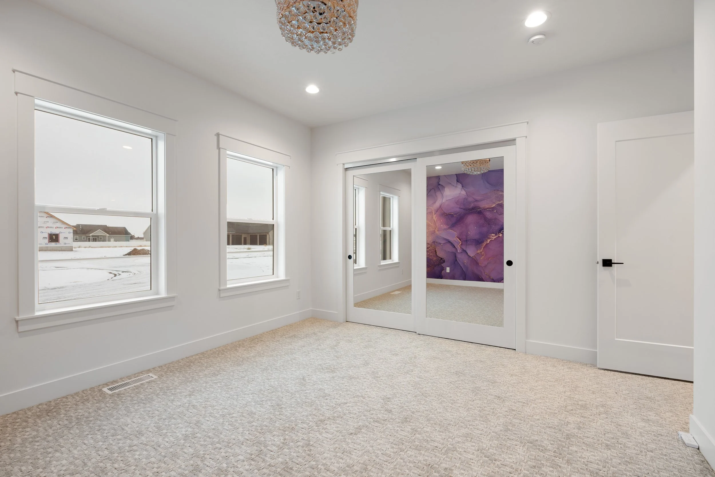 Carpeted bedroom with white doors and decorative ceiling light — JAB Construction’s Timeless Craftsman custom home in Iona, Idaho.