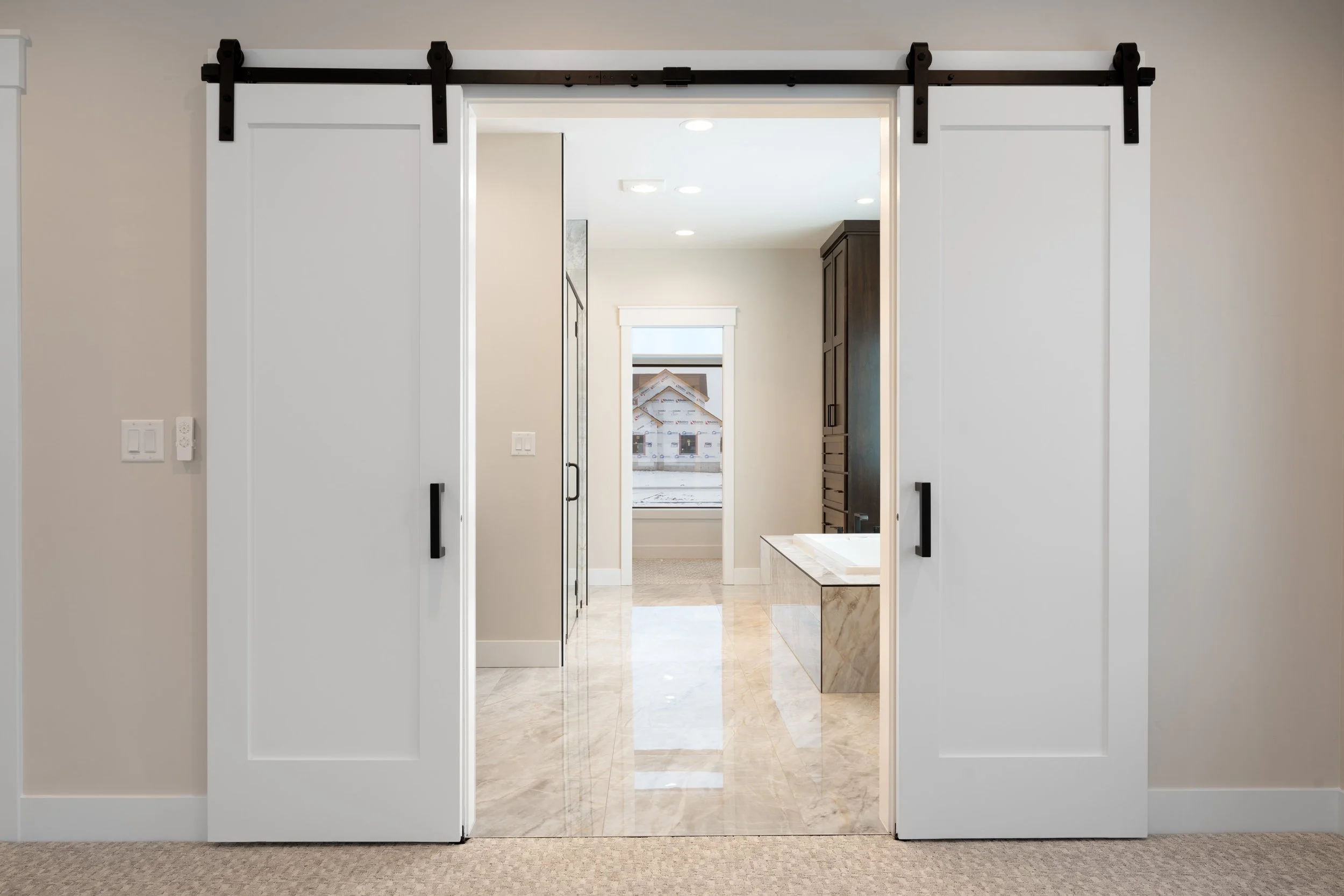 White sliding barn doors opening to an adjoining room — JAB Construction’s Timeless Craftsman custom home in Iona, Idaho.