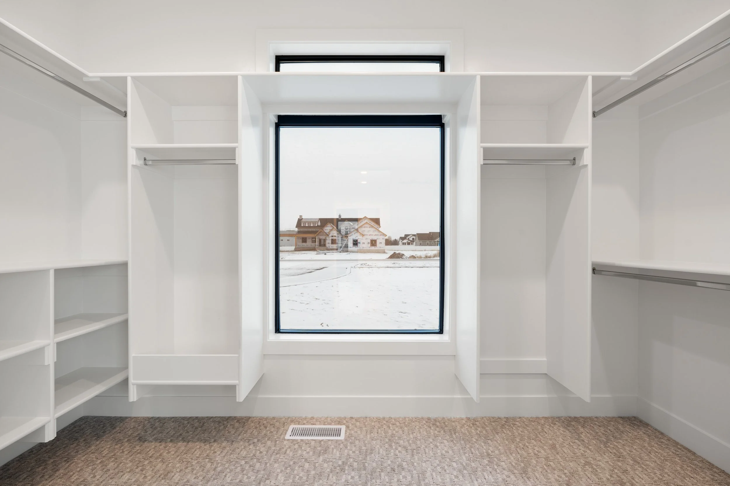 Walk-in closet with white shelves and a window — JAB Construction’s Timeless Craftsman custom home in Iona, Idaho.