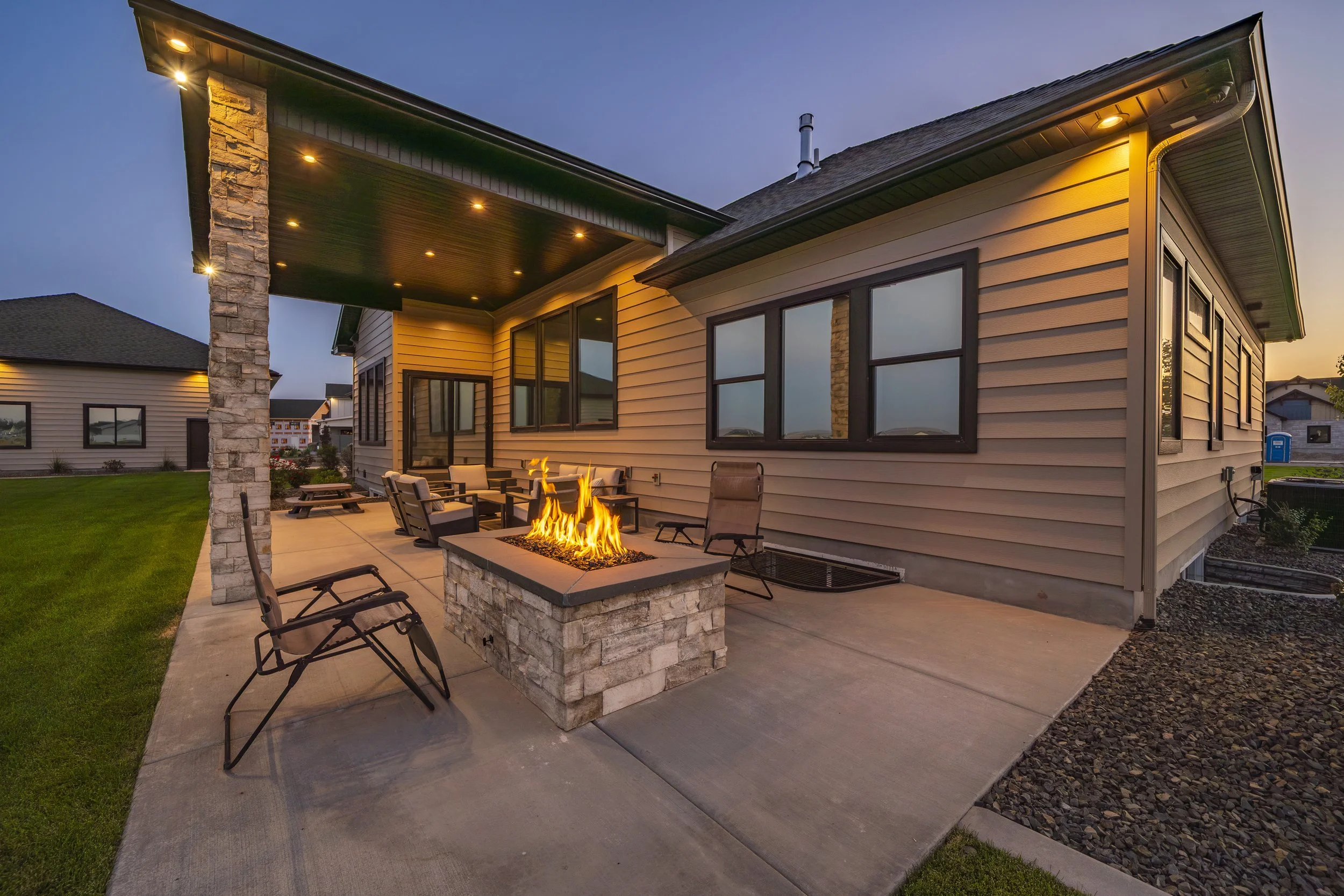 Rear patio with seating and an illuminated fire pit — JAB Construction’s Timeless Craftsman custom home in Iona, Idaho.