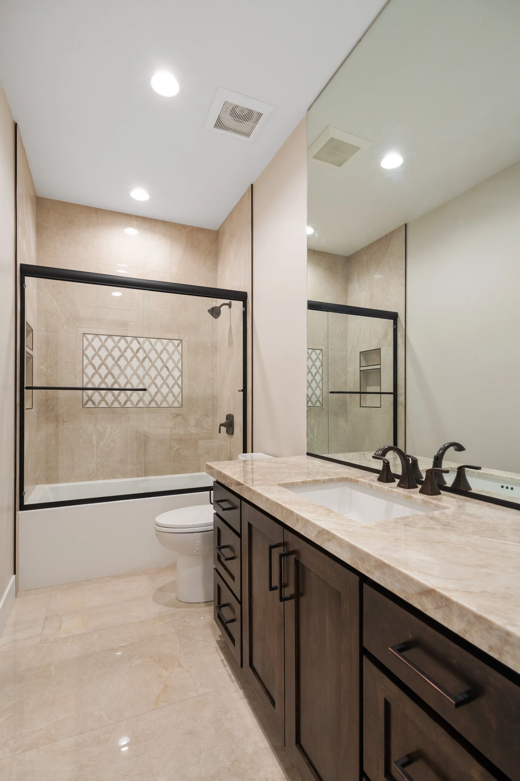 Bathroom with a dark vanity and patterned shower surround — JAB Construction’s Timeless Craftsman custom home in Iona, Idaho.