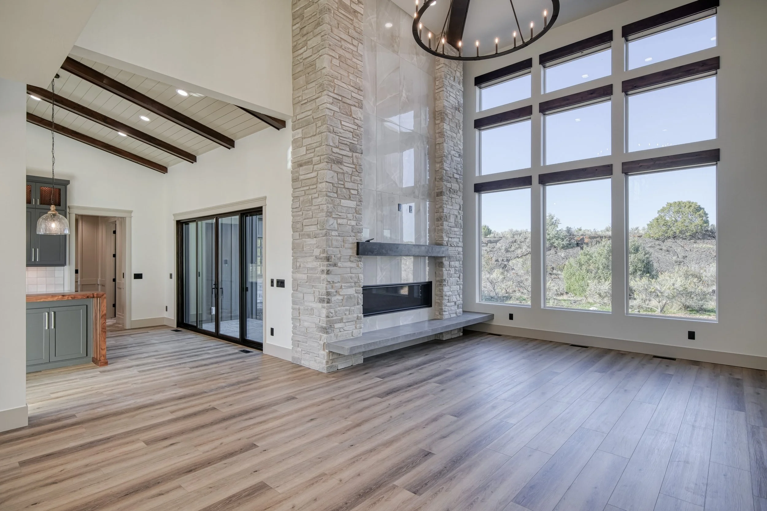 Living room with a stone fireplace beside tall windows — JAB Construction’s Modern Transitional custom home in Blackfoot, Idaho.