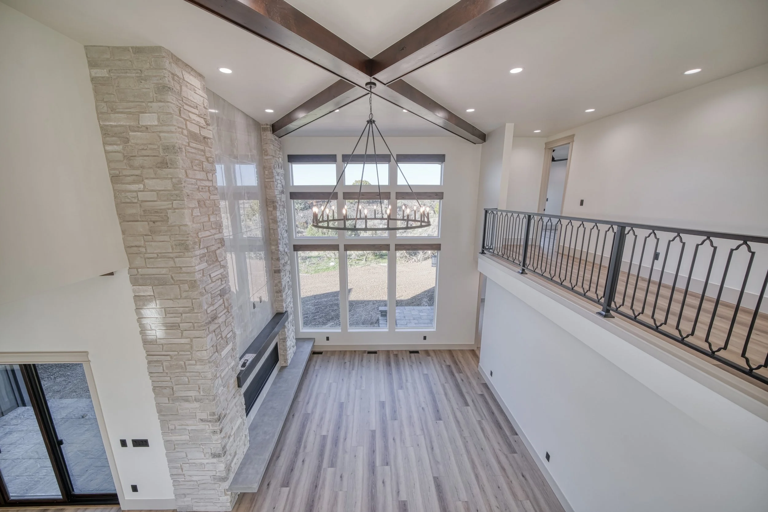 Upper hallway overlooking tall windows and a fireplace — JAB Construction’s Modern Transitional custom home in Blackfoot, Idaho.