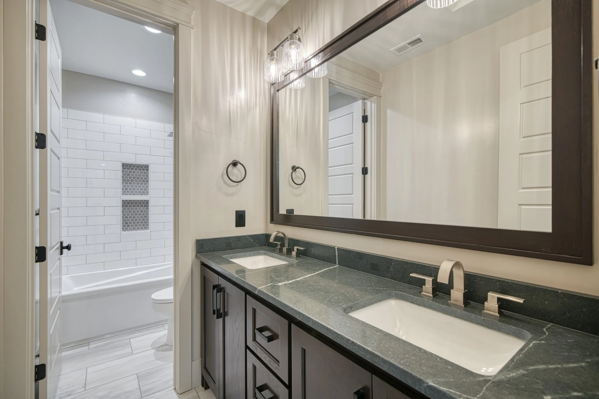 Bathroom vanity with dark cabinets and a long mirror — JAB Construction’s Modern Transitional custom home in Blackfoot, Idaho.