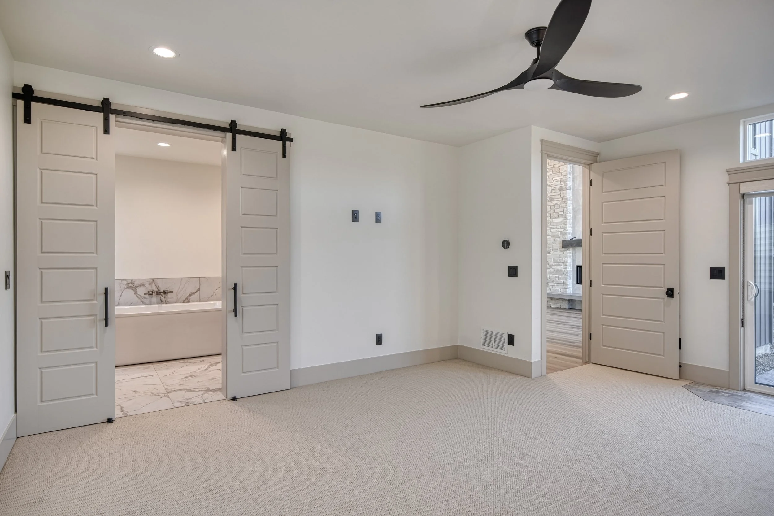 Carpeted bedroom with white walls and a ceiling fan — JAB Construction’s Modern Transitional custom home in Blackfoot, Idaho.
