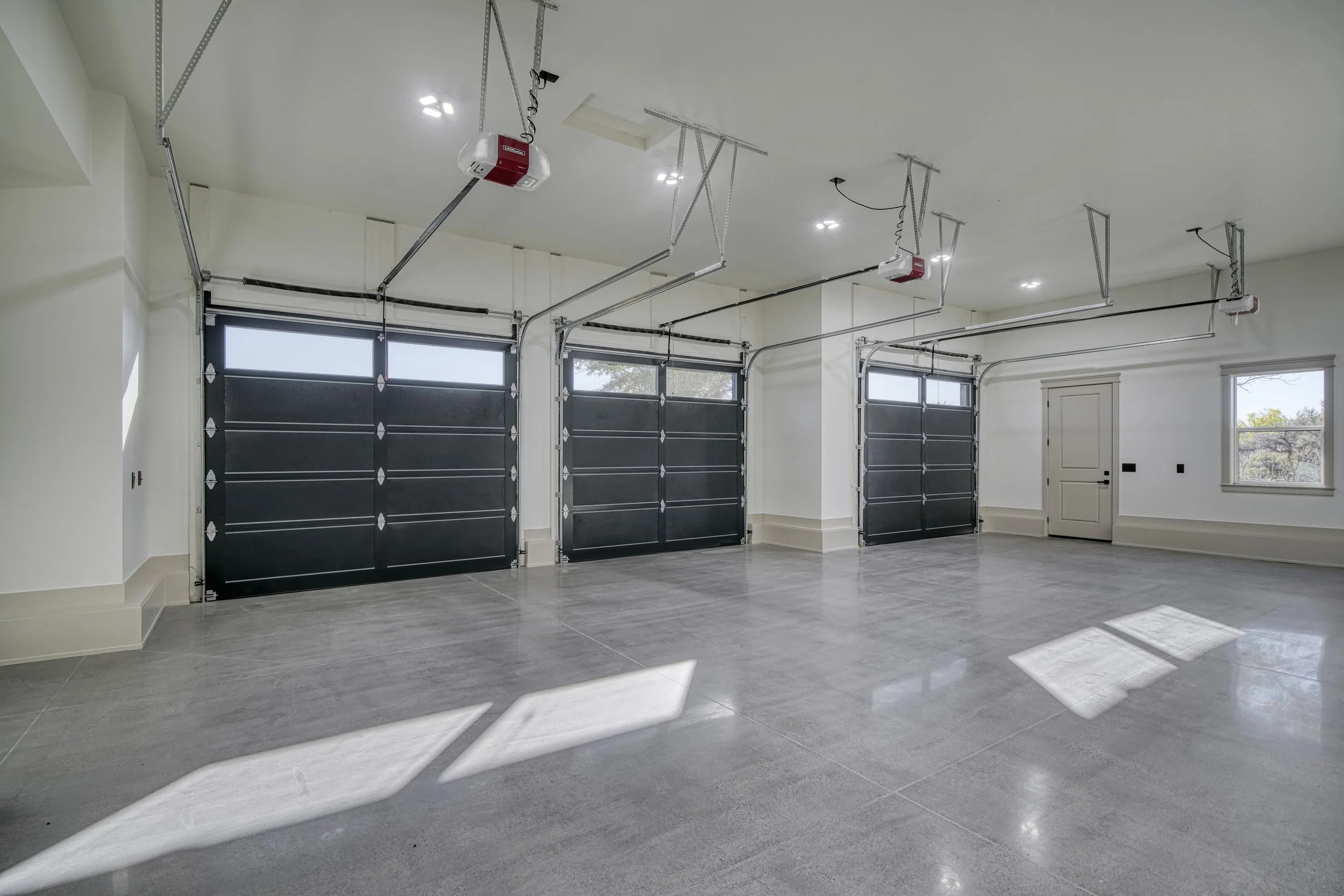 Three-car garage interior with overhead doors — JAB Construction’s Modern Transitional custom home in Blackfoot, Idaho.