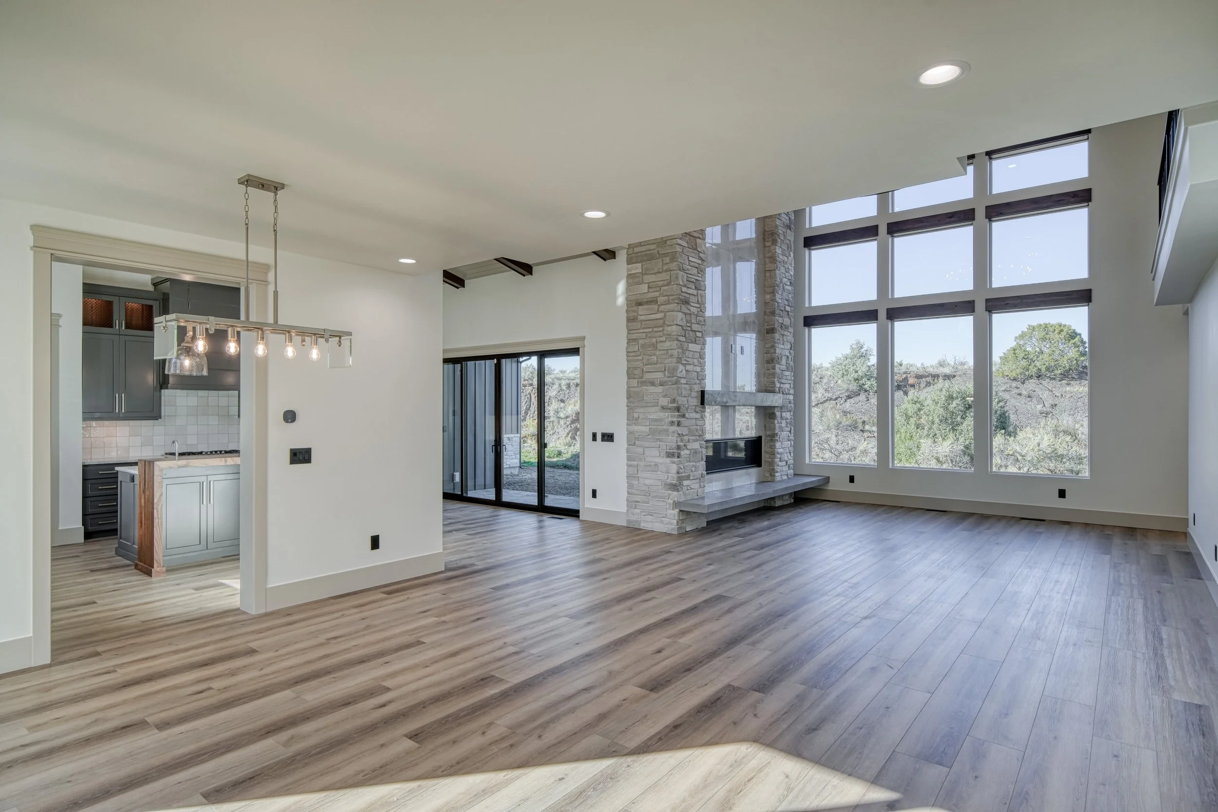 Tall living area with floor-to-ceiling windows and a fireplace — JAB Construction’s Modern Transitional custom home in Blackfoot, Idaho.