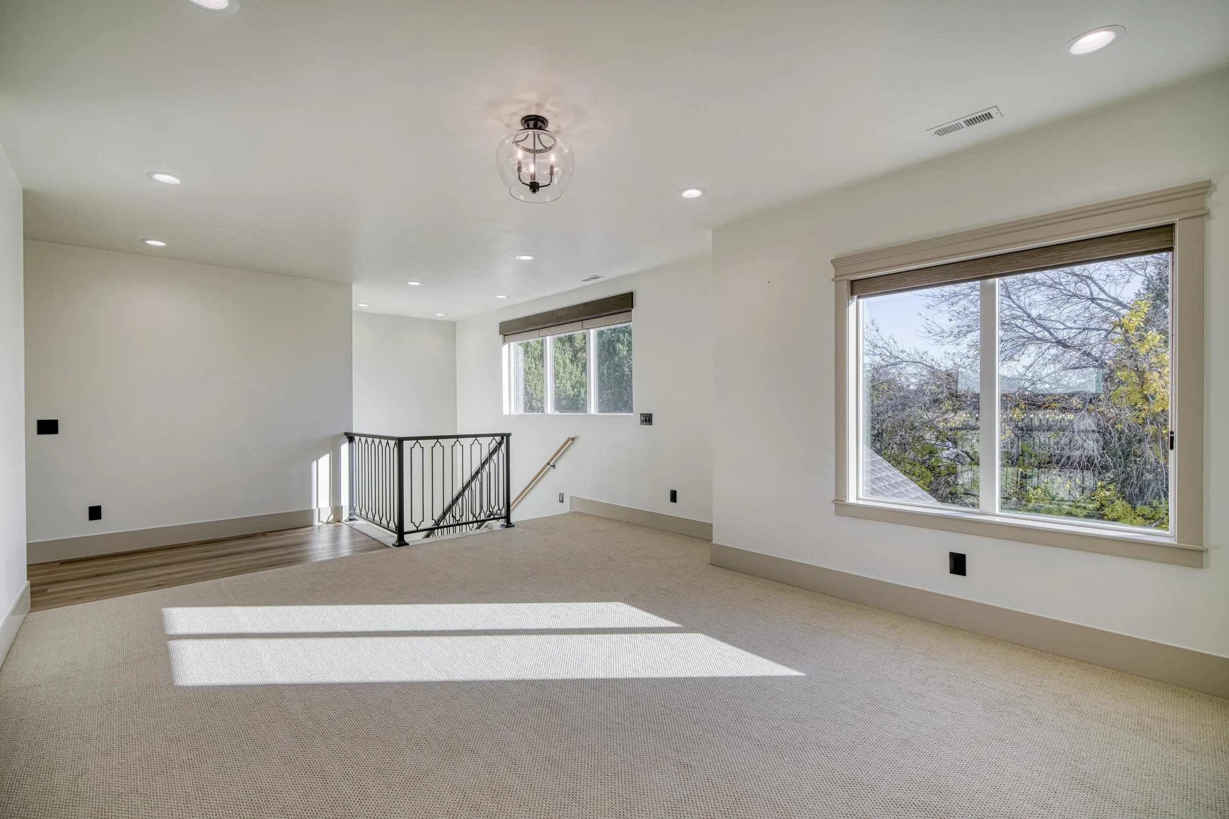 Carpeted room with broad windows and recessed lighting — JAB Construction’s Modern Transitional custom home in Blackfoot, Idaho.