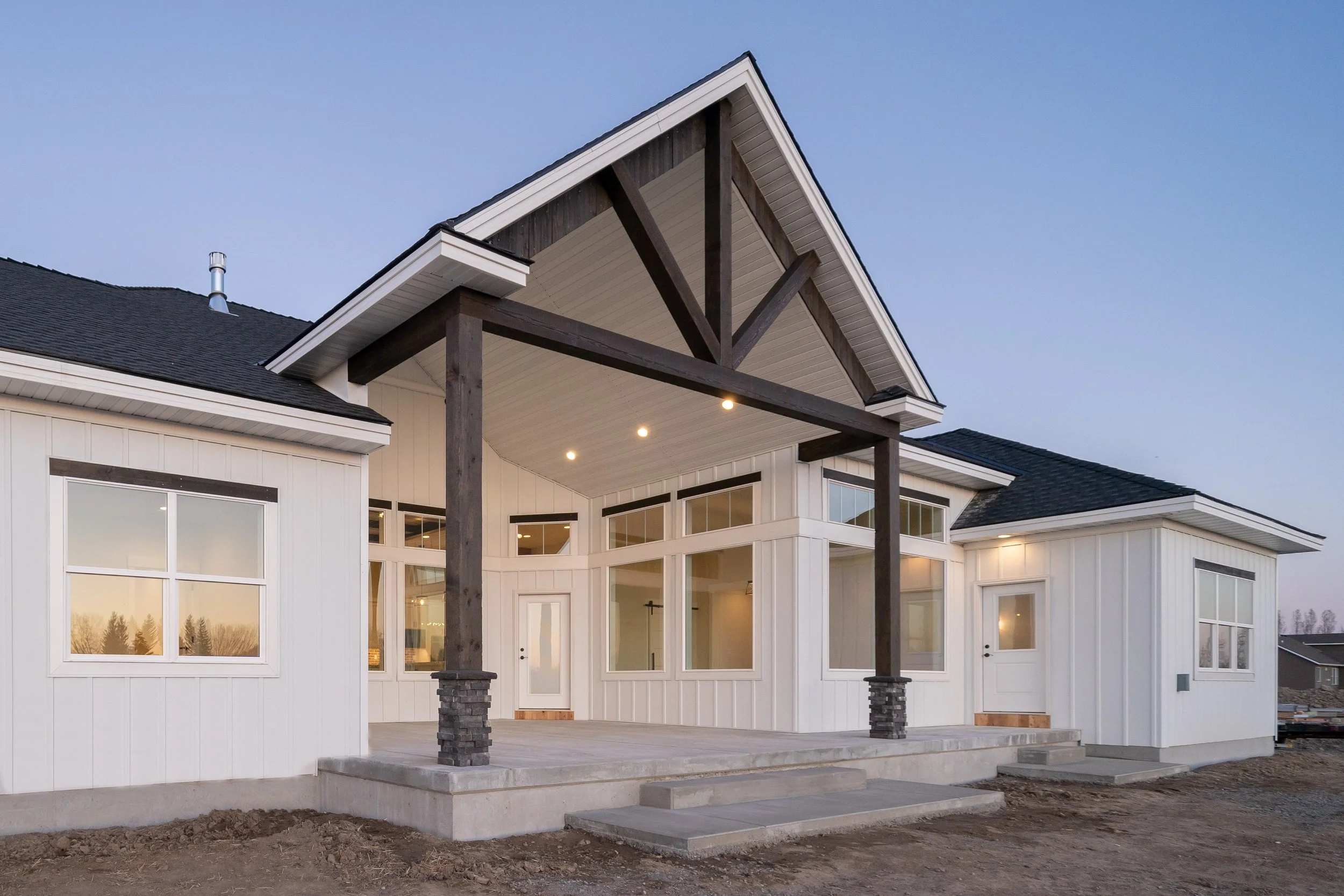 Rear home exterior with a gabled covered patio and timber columns at JAB Construction’s Country Craftsman custom home in Shelley, Idaho.