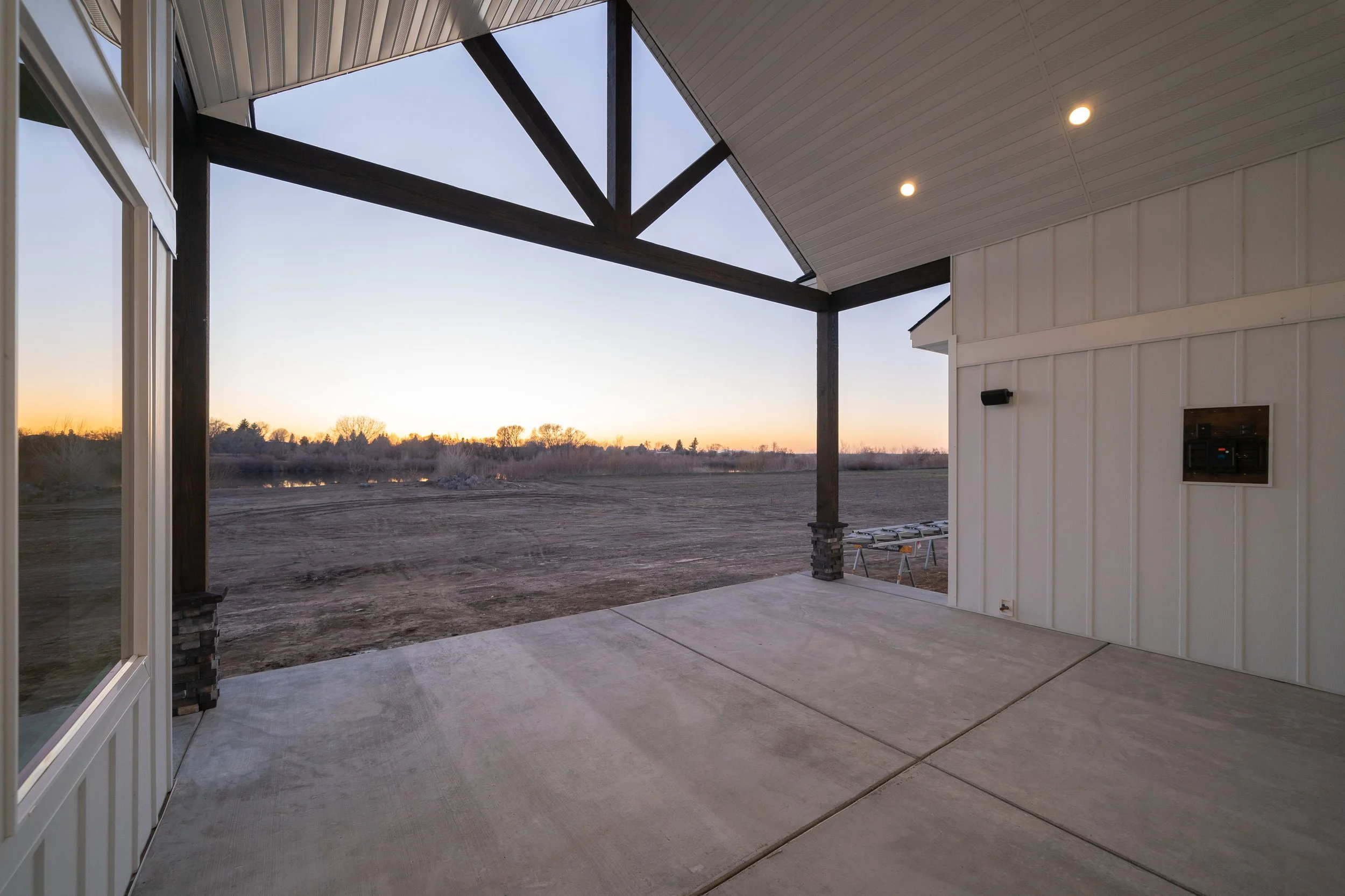 Covered porch with timber beams overlooking open land at JAB Construction’s Country Craftsman custom home in Shelley, Idaho.