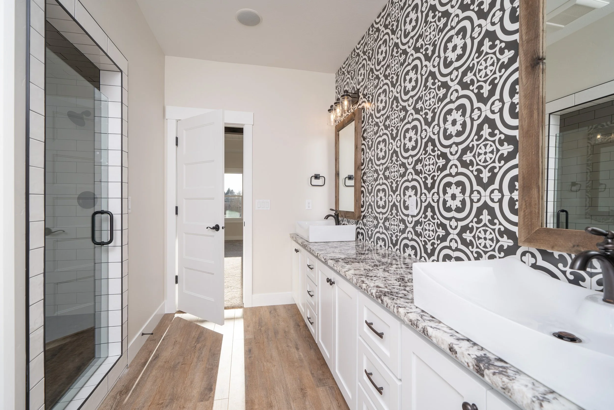 Bathroom with patterned tile, double sinks and a glass shower at JAB Construction’s Country Craftsman custom home in Shelley, Idaho.