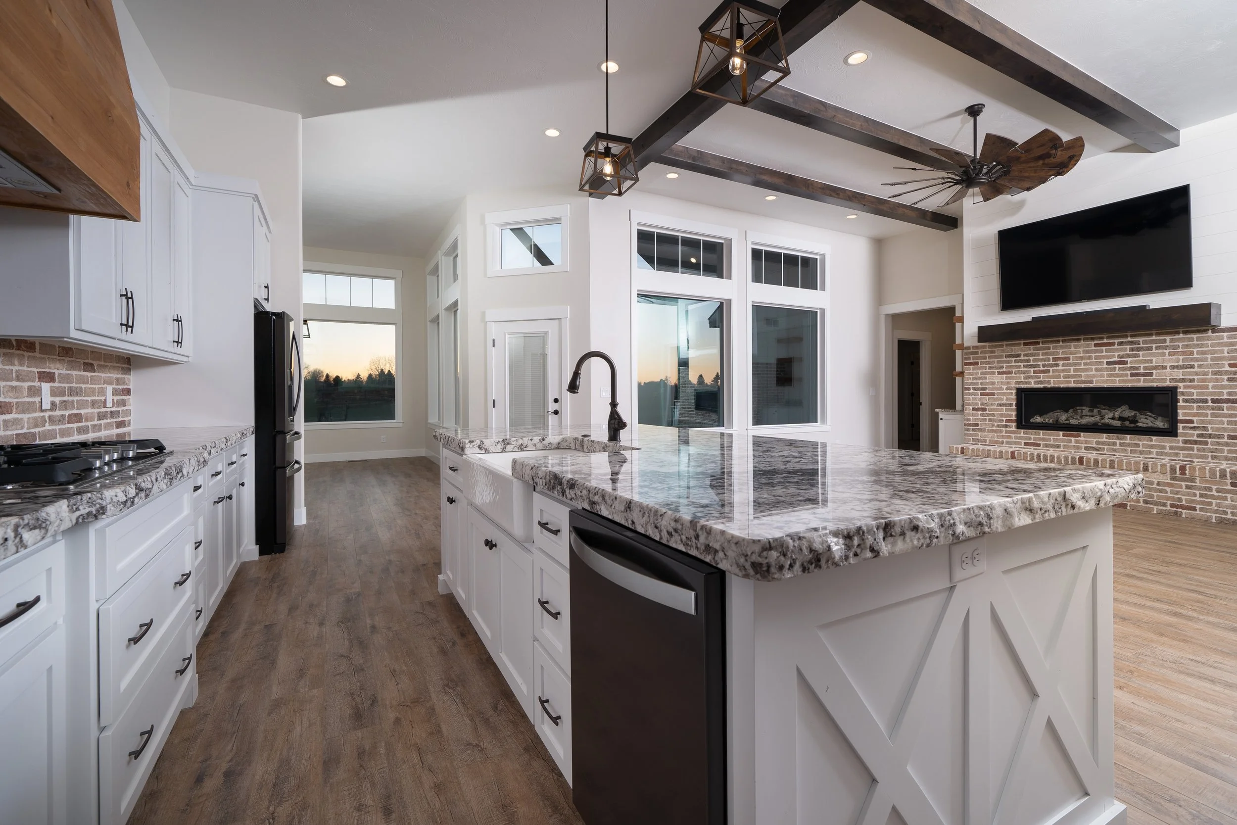 Kitchen with white cabinets, large windows and a ceiling fan at JAB Construction’s Country Craftsman custom home in Shelley, Idaho.