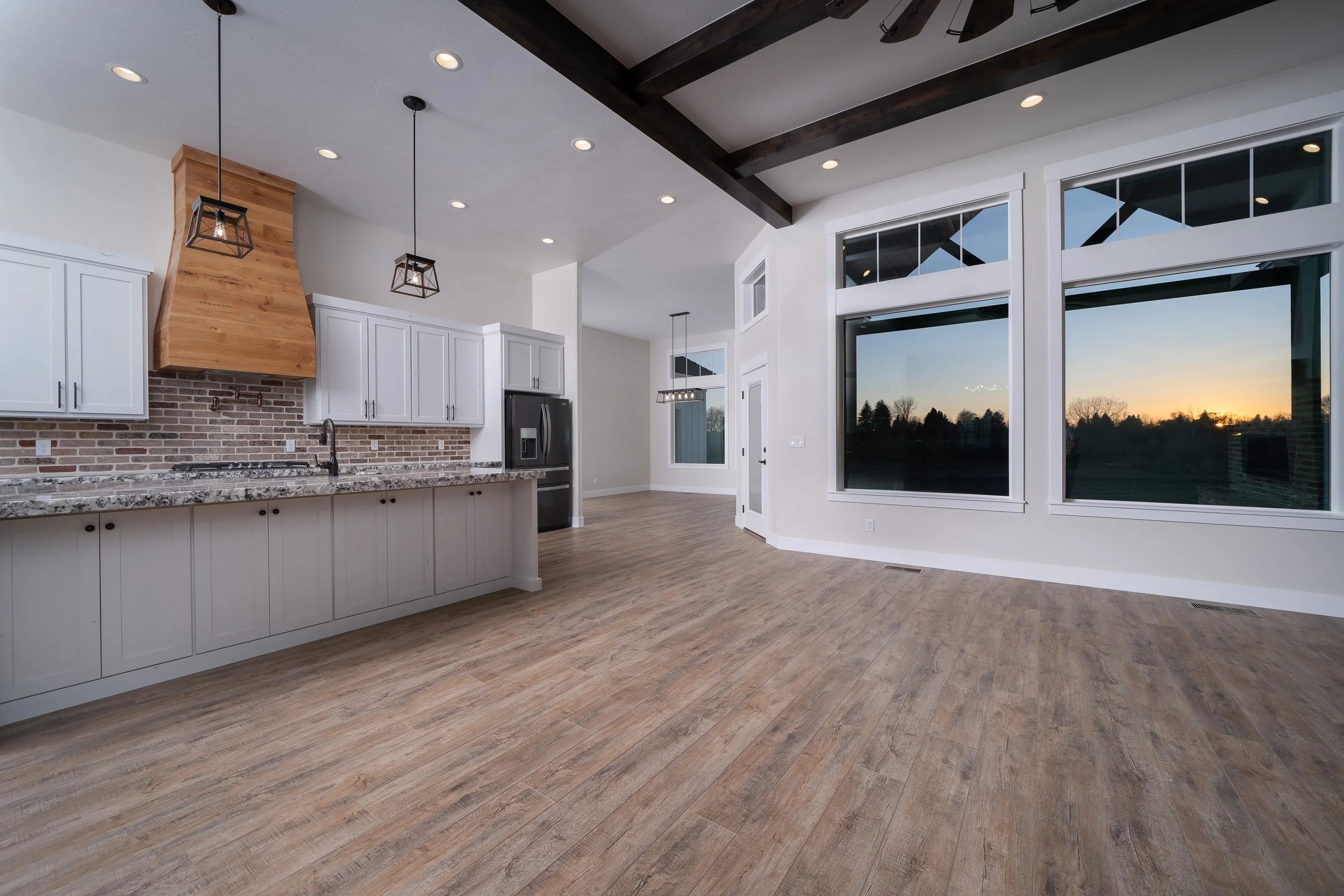 Open kitchen and living area with white cabinets and brick accents at JAB Construction’s Country Craftsman custom home in Shelley, Idaho.