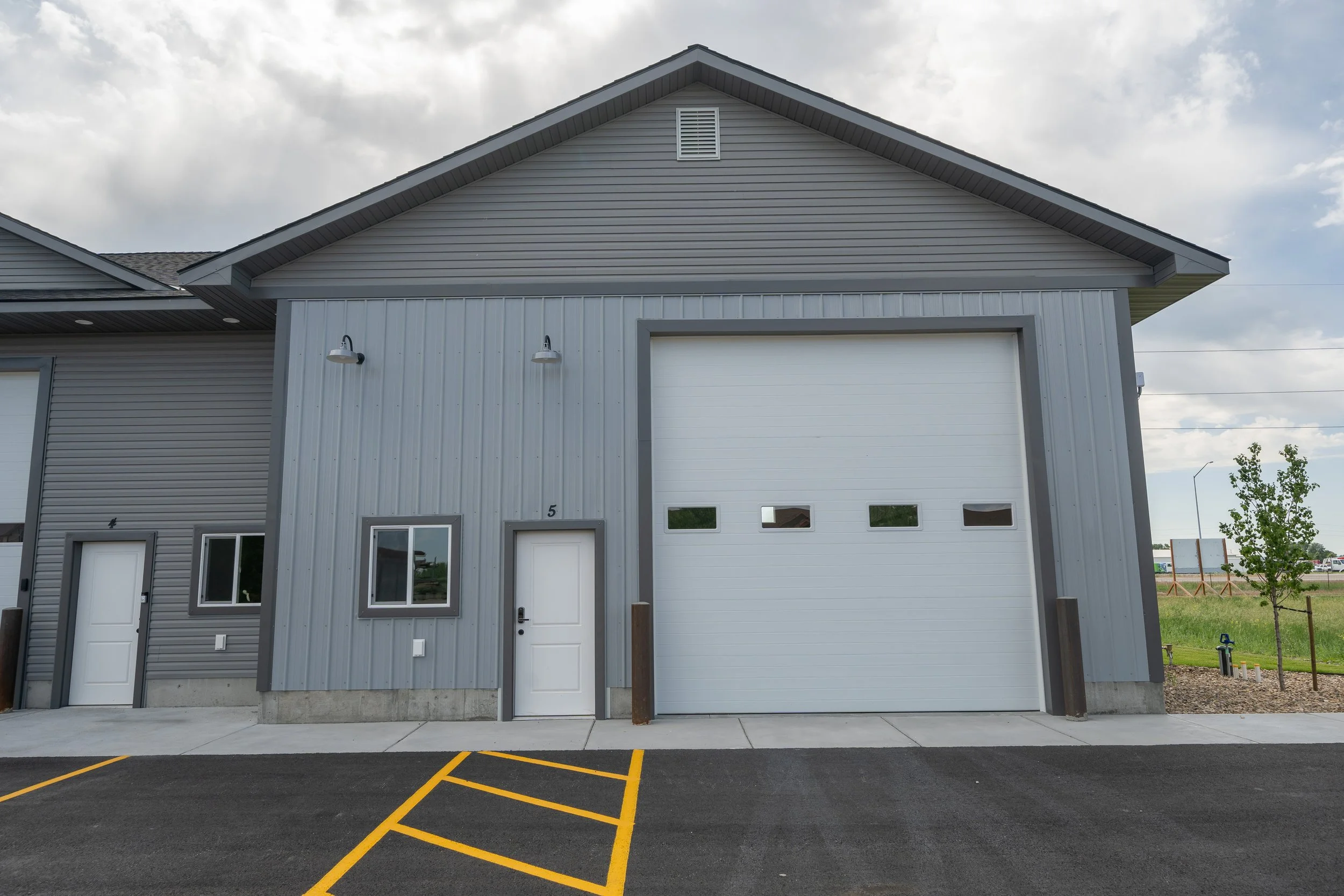 Commercial unit entrance and overhead garage door beside accessible parking — JAB Construction’s Commercial Lease Space project in Rigby, Idaho.