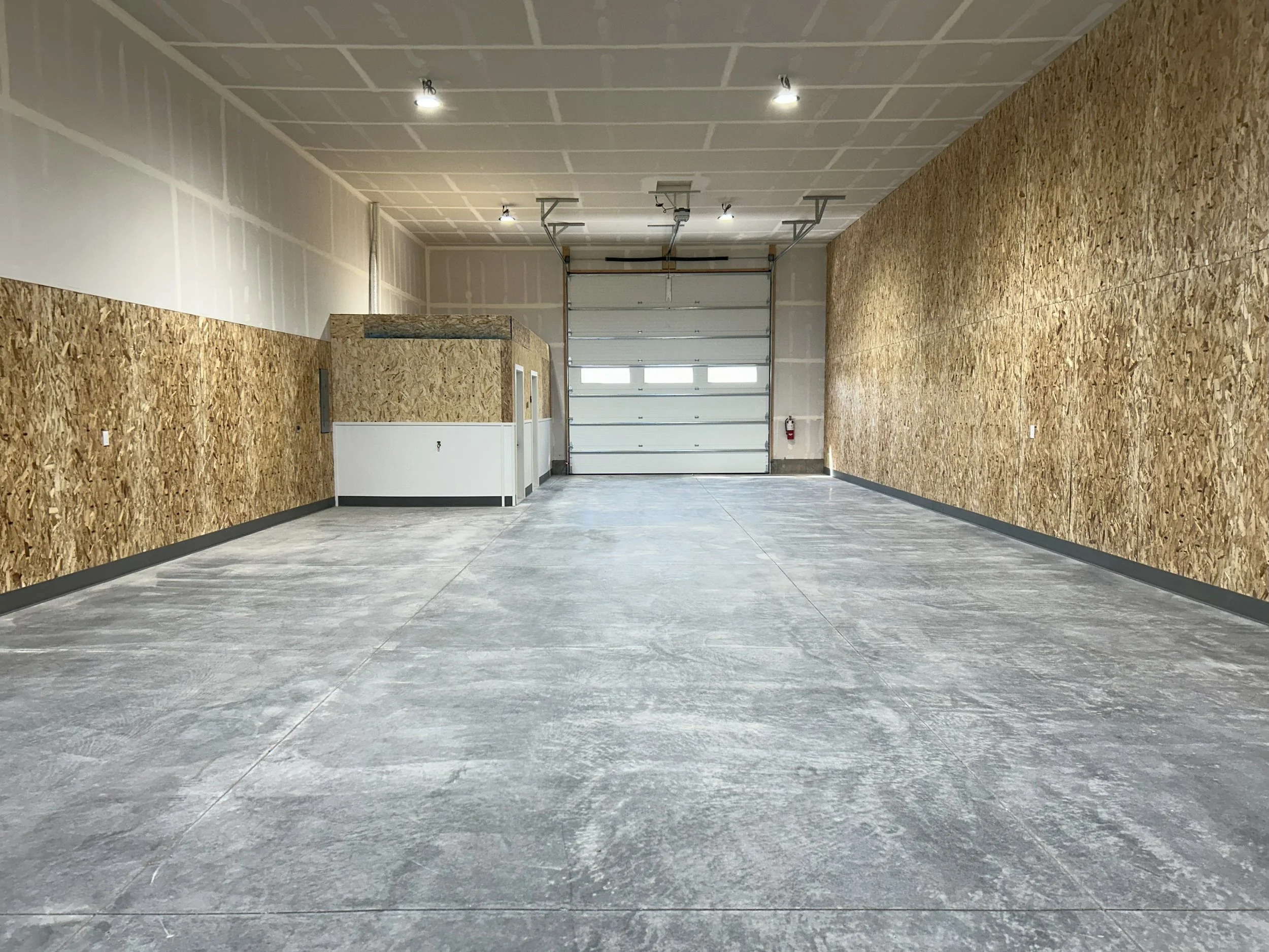 Garage bay interior facing an overhead door — JAB Construction’s Modern Commercial Lease Space project in Rigby, Idaho.