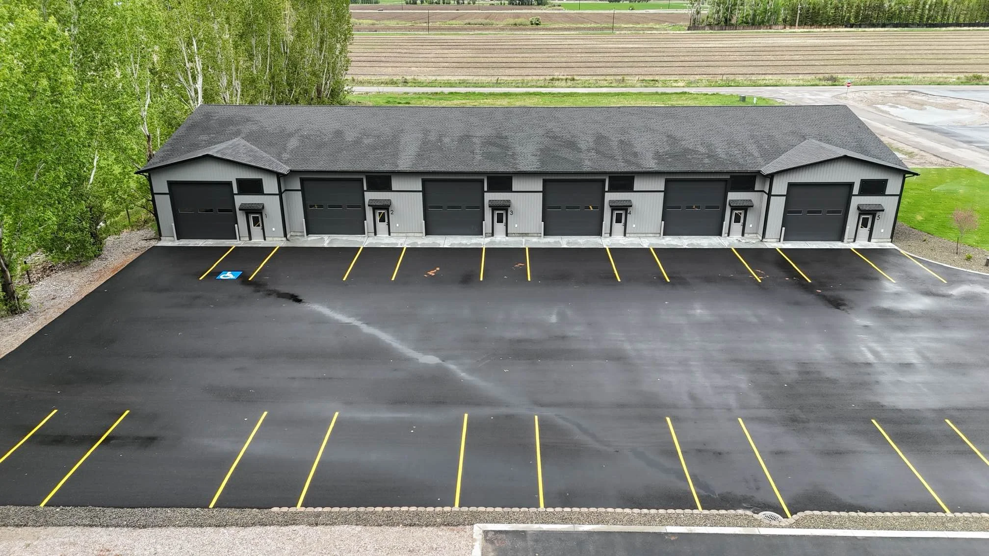 Aerial front view of commercial garage units and striped parking — JAB Construction’s Modern Commercial Lease Space project in Rigby, Idaho.