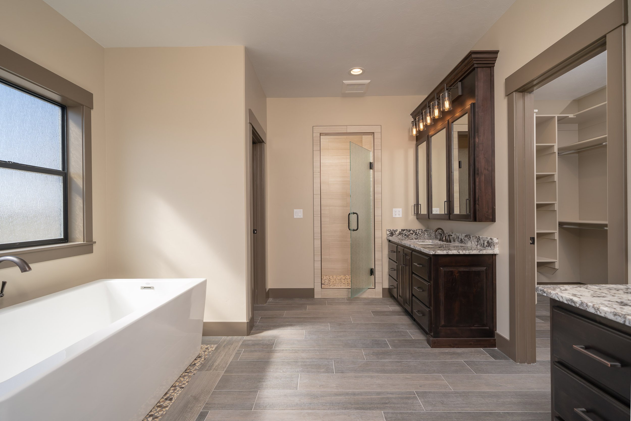 Bathroom with dark vanity cabinets and a bathtub — JAB Construction’s Stone Craftsman custom home in Roberts, Idaho.