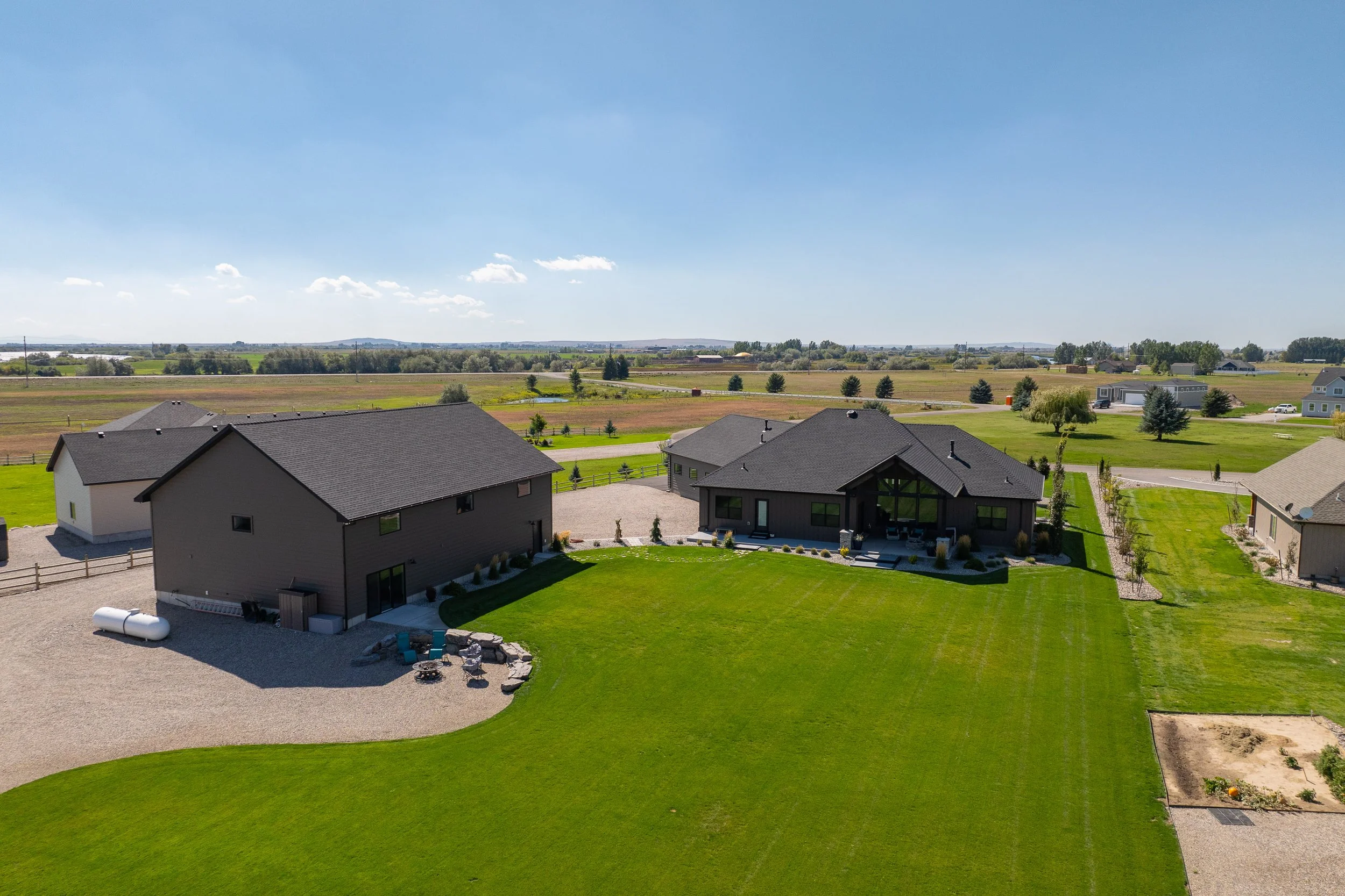Aerial view of the home, detached structure and landscaped yard — JAB Construction’s Stone Craftsman custom home in Roberts, Idaho.