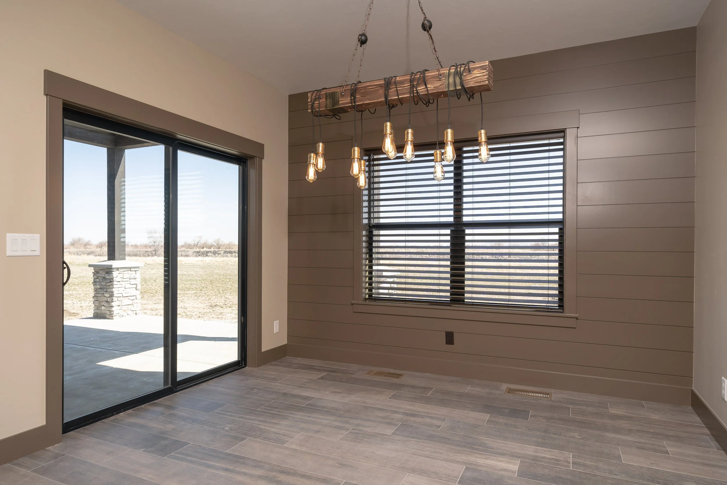 Dining area with broad windows and hanging lighting — JAB Construction’s Stone Craftsman custom home in Roberts, Idaho.