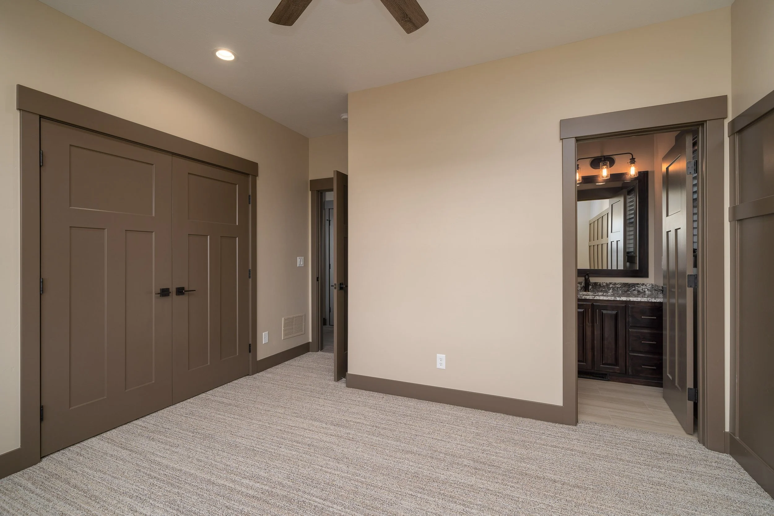 Bedroom with dark doors and adjoining doorway — JAB Construction’s Stone Craftsman custom home in Roberts, Idaho.