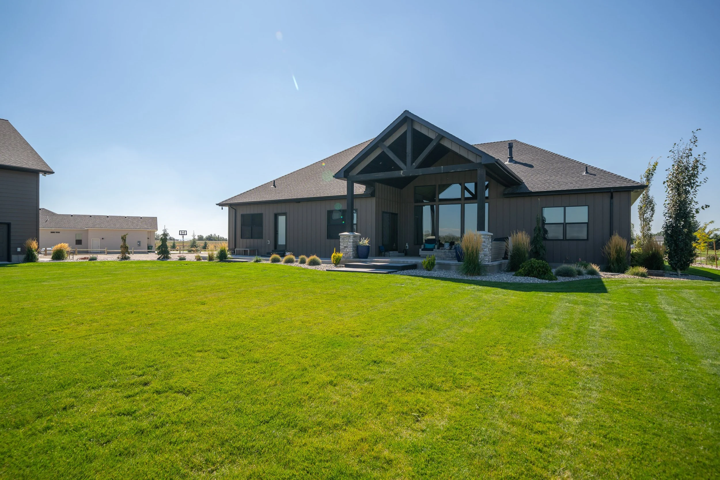 Rear exterior viewed across a broad lawn — JAB Construction’s Stone Craftsman custom home in Roberts, Idaho.