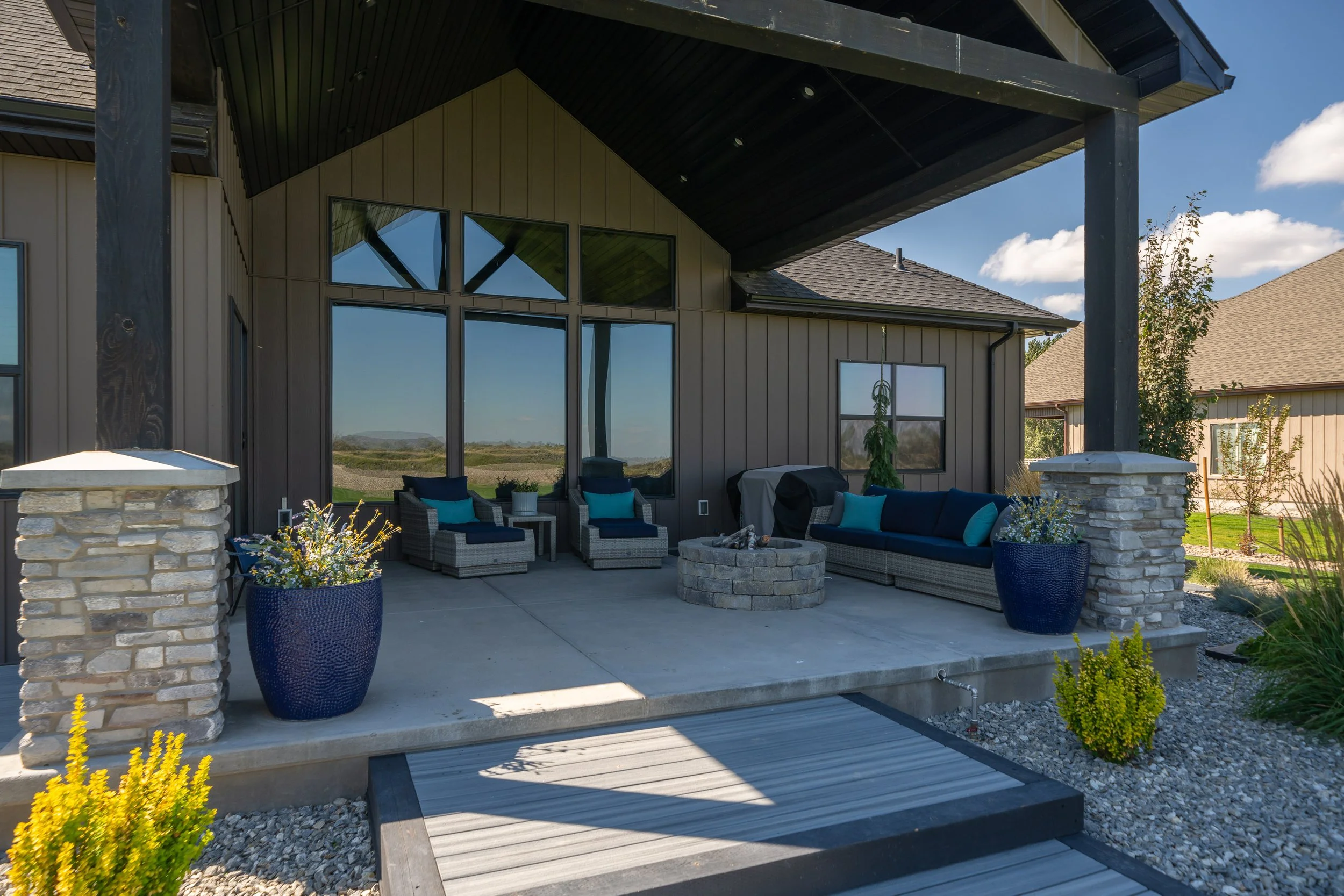 Covered patio with outdoor seating and tall rear windows — JAB Construction’s Stone Craftsman custom home in Roberts, Idaho.