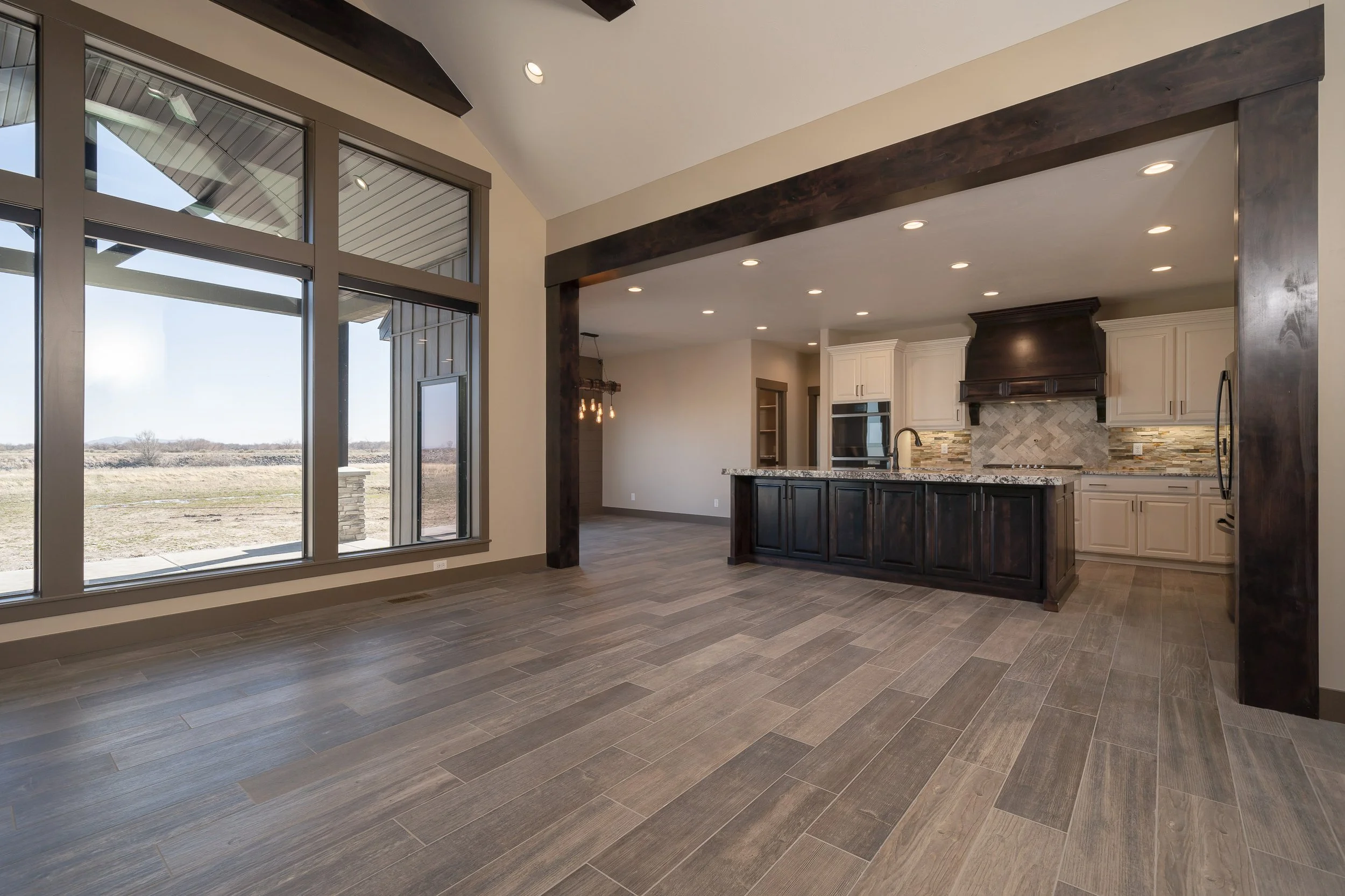 Open living and kitchen area with ceiling beams — JAB Construction’s Stone Craftsman custom home in Roberts, Idaho.