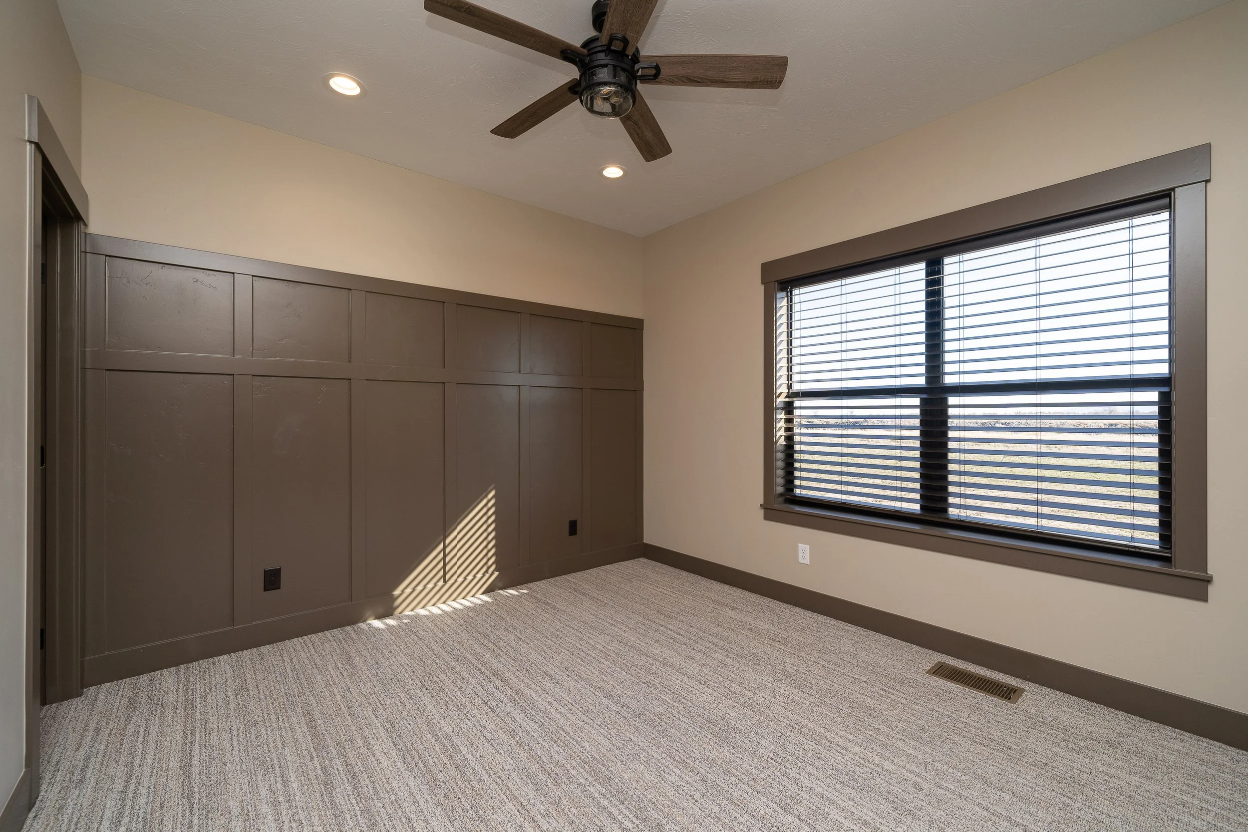 Carpeted bedroom with a ceiling fan and large window — JAB Construction’s Stone Craftsman custom home in Roberts, Idaho.