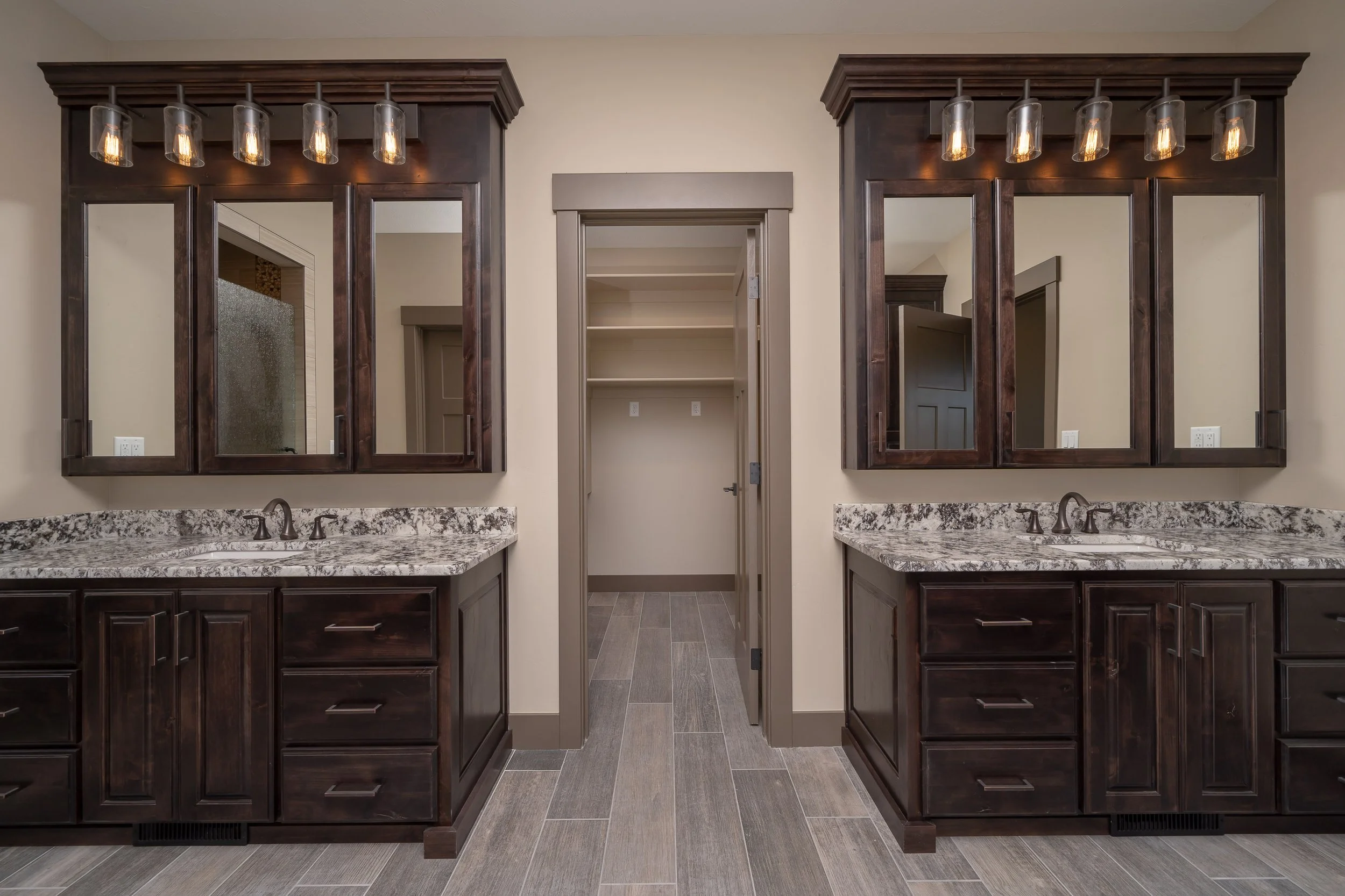 Double bathroom vanities with framed mirrors — JAB Construction’s Stone Craftsman custom home in Roberts, Idaho.